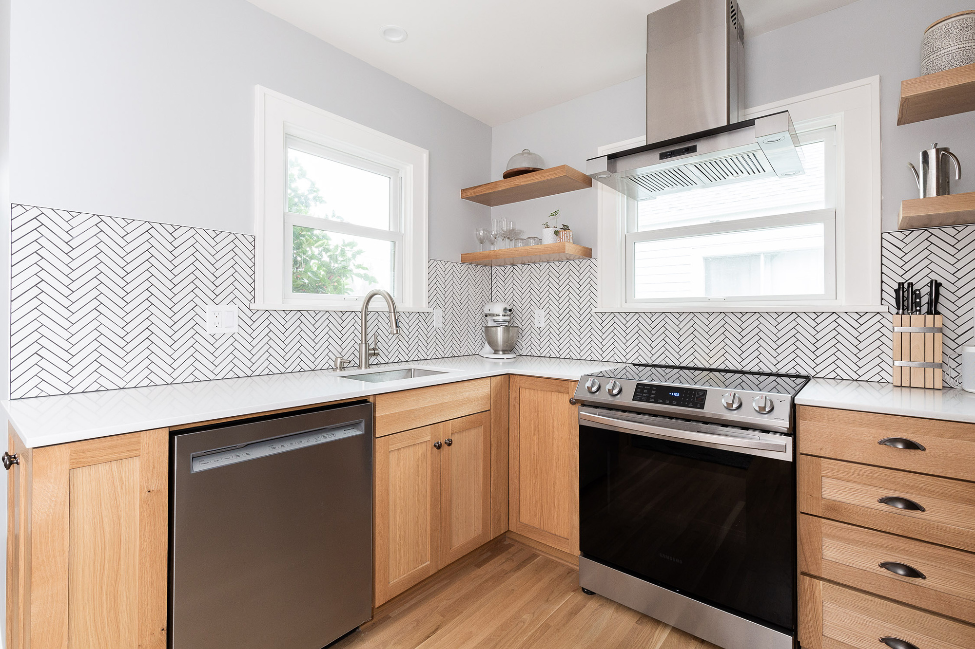 L-shaped kitchen work area with white oak cabinets, white quartz countertops, and herringbone tile backsplash seen from the corner, Arbor Lodge Kitchen remodel by Tweto Architecture