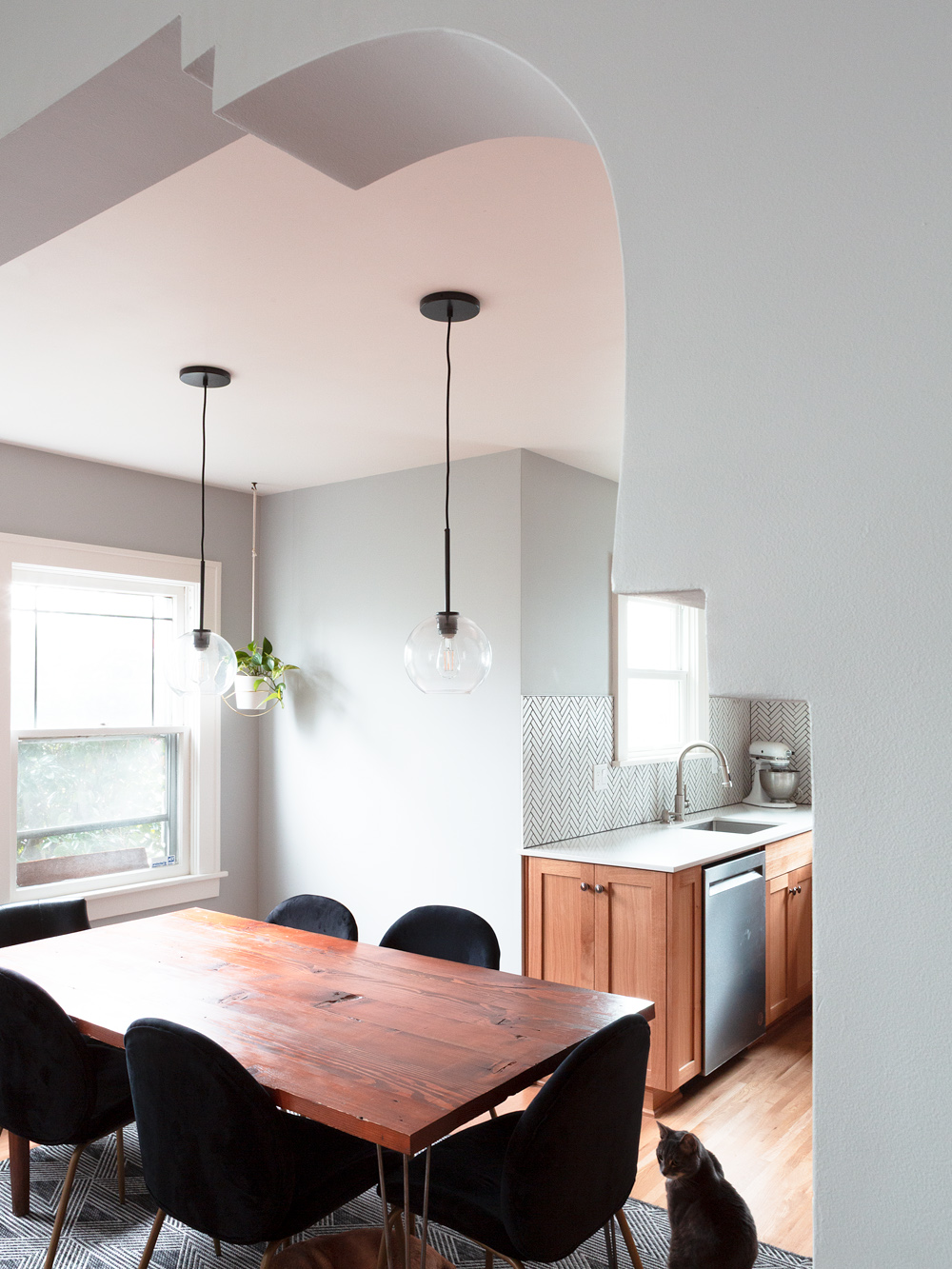 Dining room seen through the reconstructed decorative archway, with pendant lights and kitchen visible beyond, Arbor Lodge Kitchen remodel by Tweto Architecture