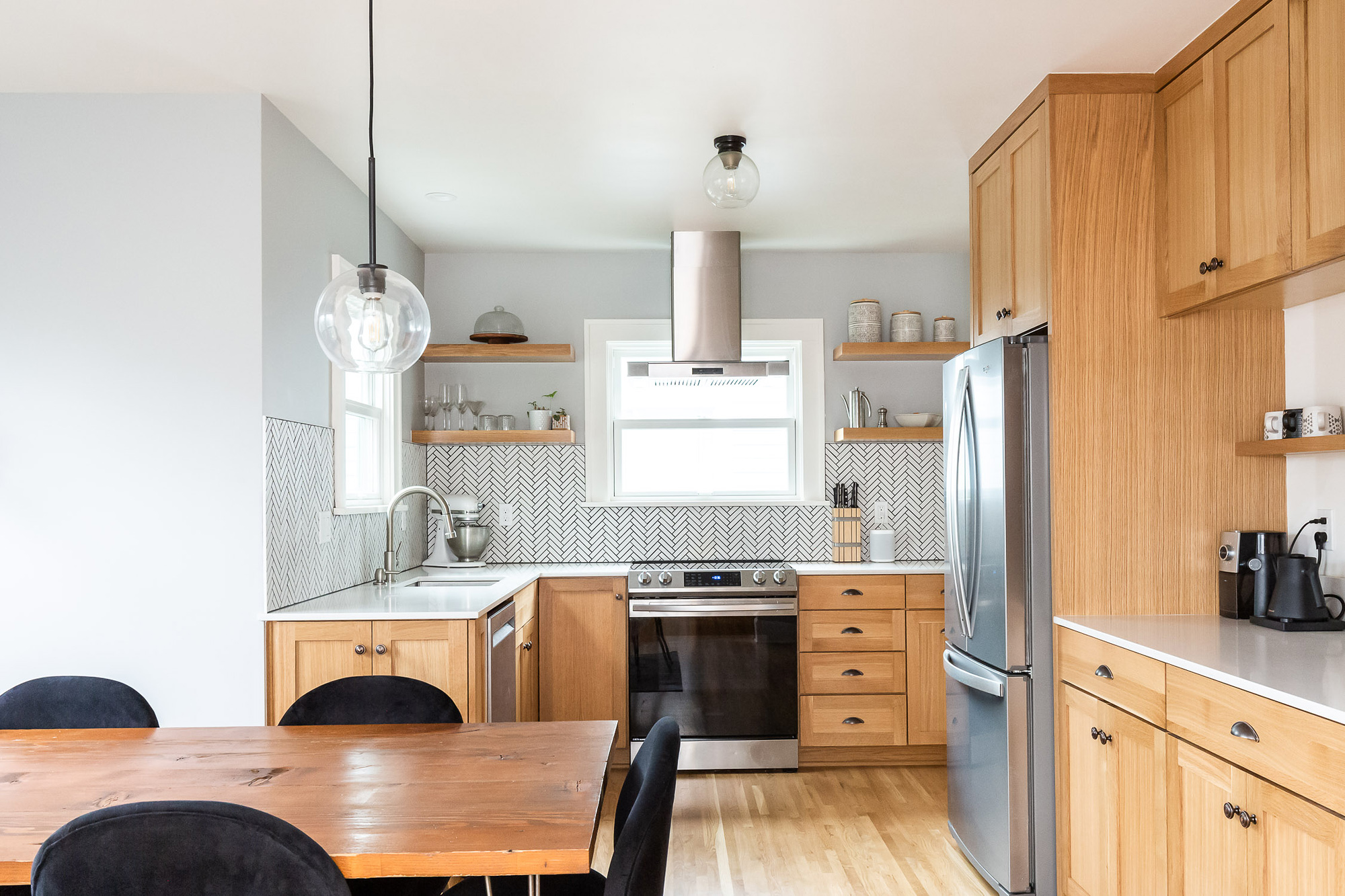 Kitchen viewed from the dining area showing range, sink, herringbone backsplash, and pantry wall with refrigerator to the right, Arbor Lodge Kitchen by Tweto Architecture