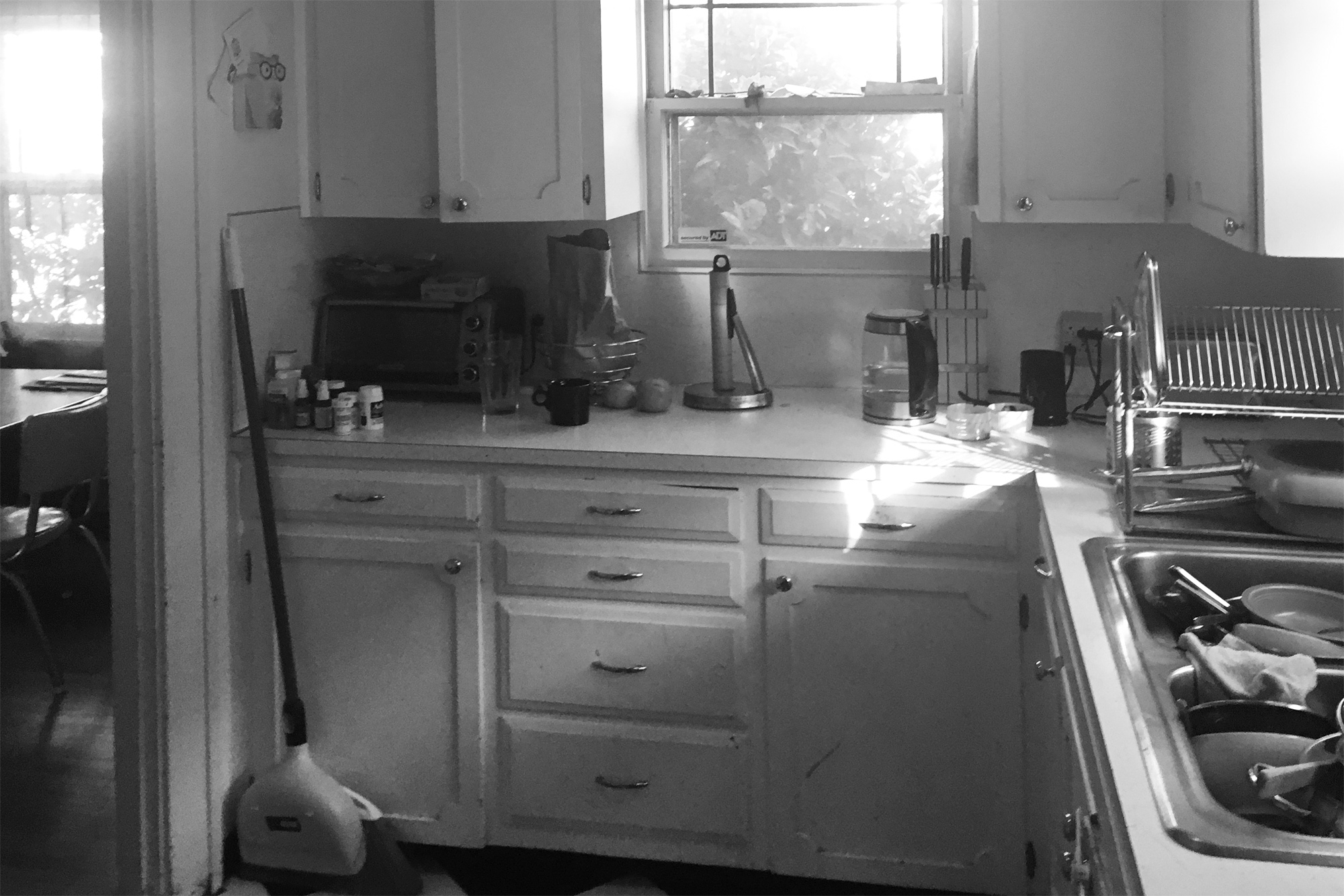 Existing kitchen before remodel — cramped 1970s layout with white laminate cabinets and small openings to the dining room, Arbor Lodge Kitchen