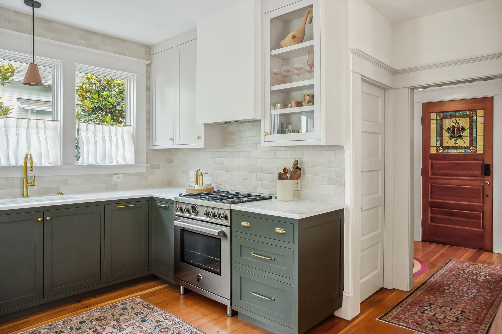 Kitchen seen from the entry, with the original stained-glass front door at right and range wall and sink visible ahead, Baldwin Street remodel by Tweto Architecture