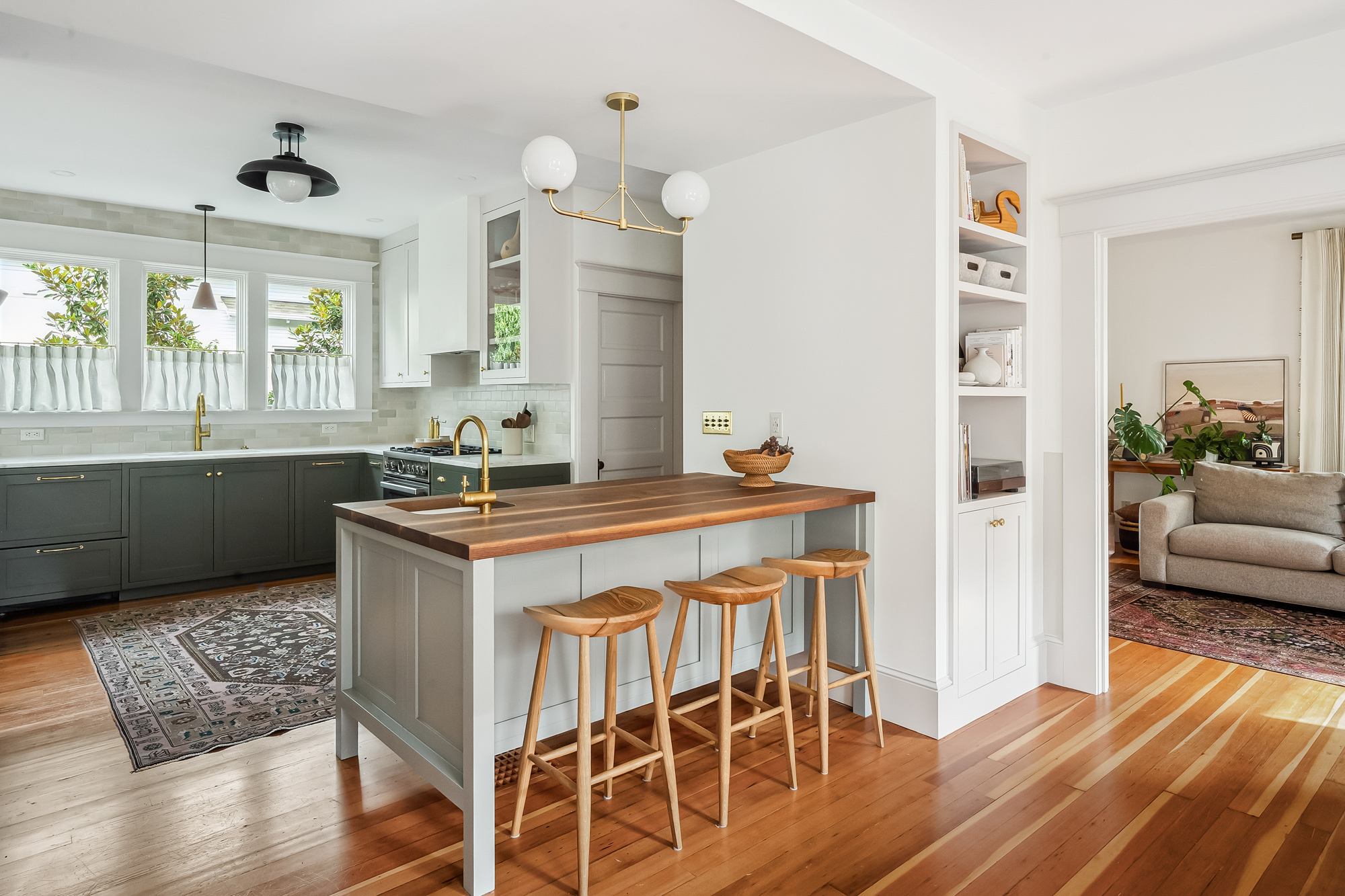 Island with walnut countertop and three bar stools, kitchen and open shelving beyond, Baldwin Street remodel by Tweto Architecture