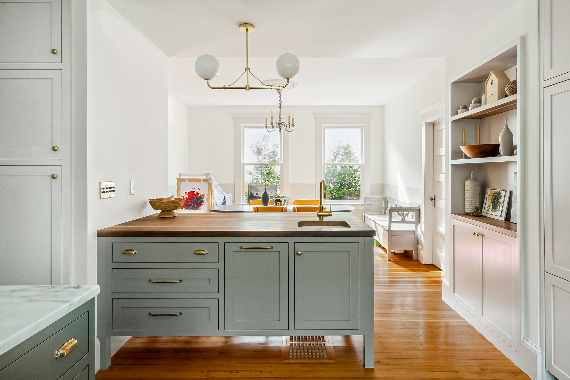Island with walnut countertop and brass faucet, open built-in shelves and dining room visible beyond, Baldwin Street remodel by Tweto Architecture