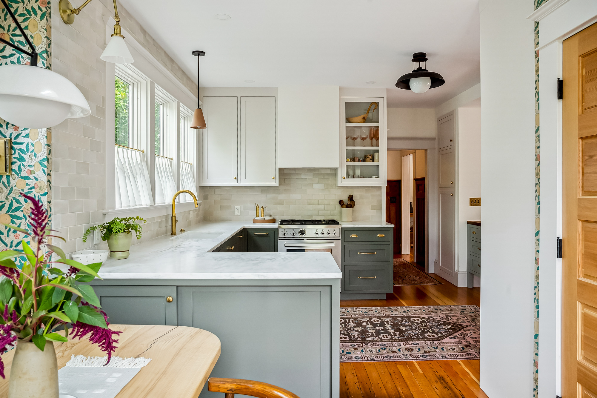 Kitchen seen from the rear seating area, showing the peninsula, range wall, and windows beyond, Baldwin Street remodel by Tweto Architecture