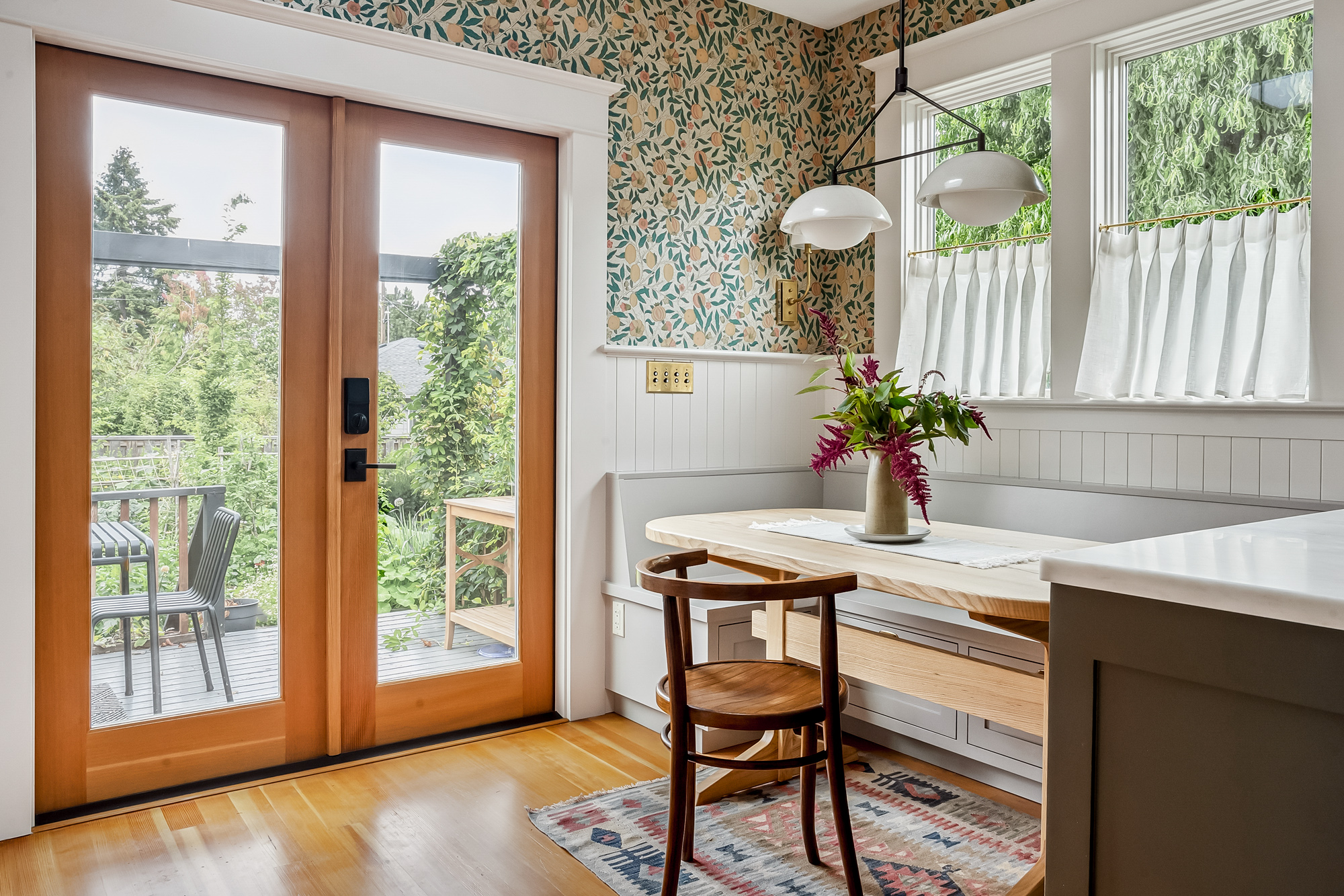 Breakfast nook with built-in bench and table, botanical wallpaper, and french doors to the backyard deck, Baldwin Street remodel by Tweto Architecture
