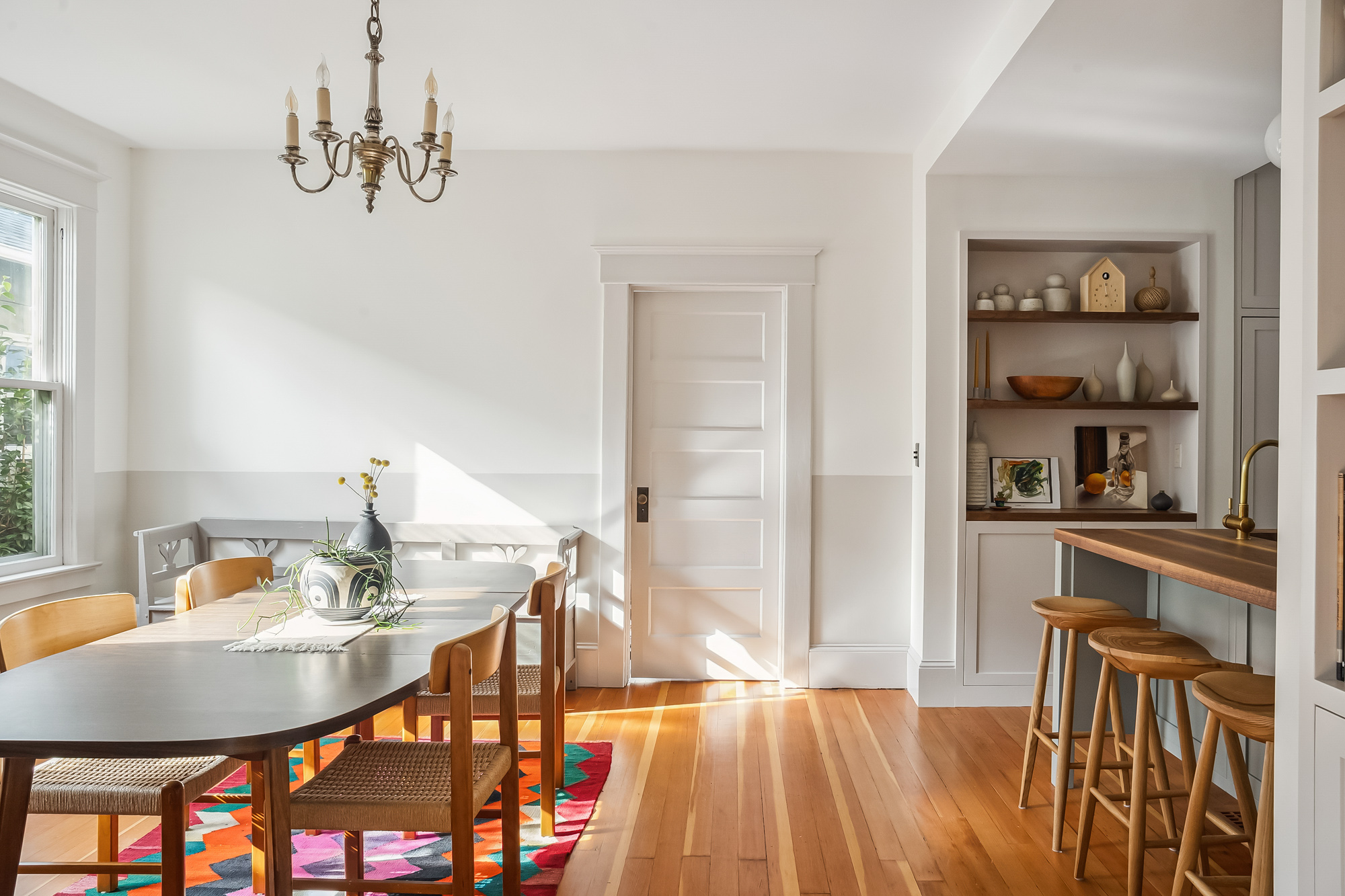 Dining room looking toward the kitchen, with the island and open display shelves visible through the opening, Baldwin Street remodel by Tweto Architecture