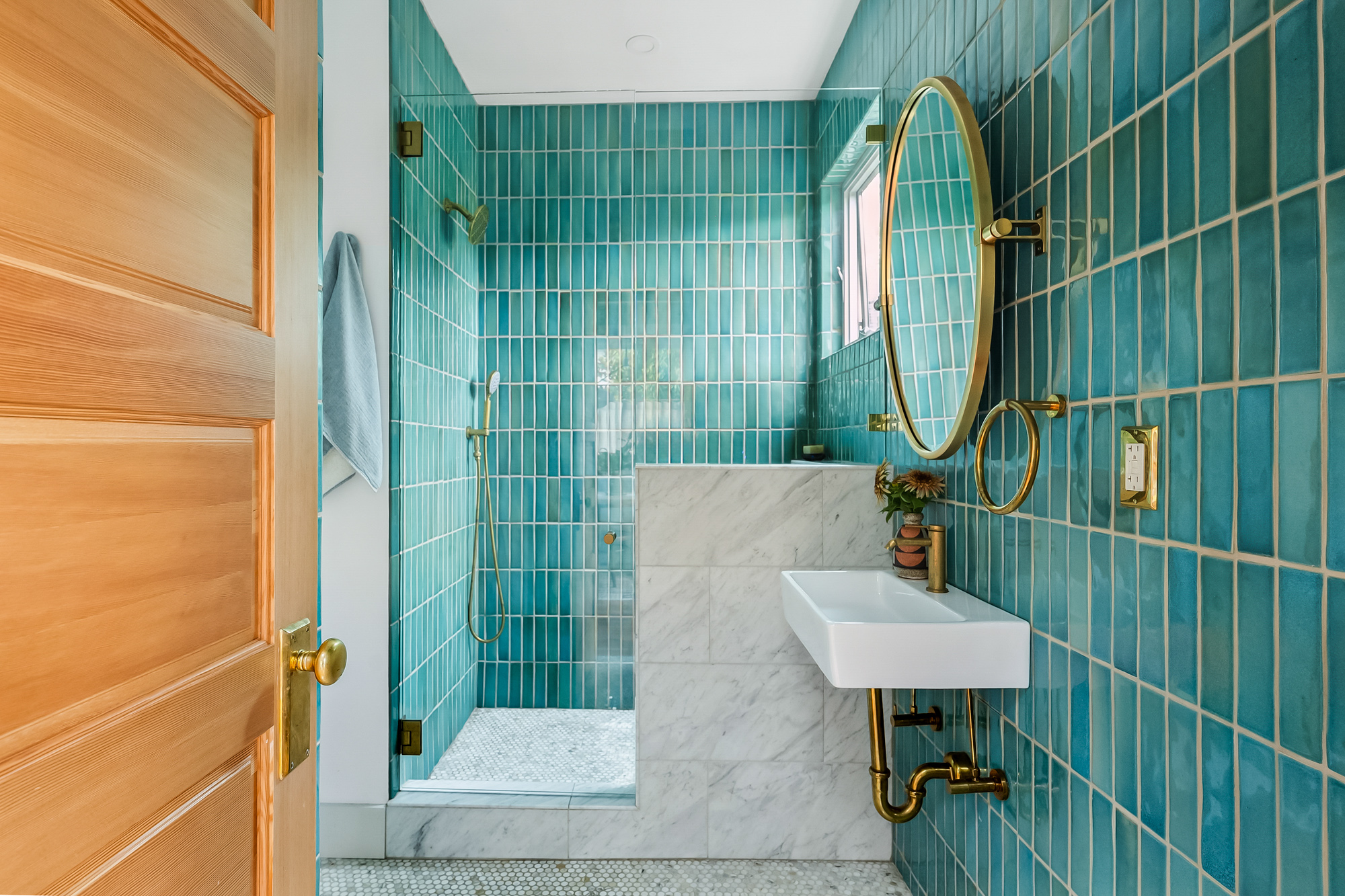 Downstairs bathroom with floor-to-ceiling hand-made Mexican teal tile, glass shower, and wall-mount sink with exposed brass plumbing, Baldwin Street remodel by Tweto Architecture