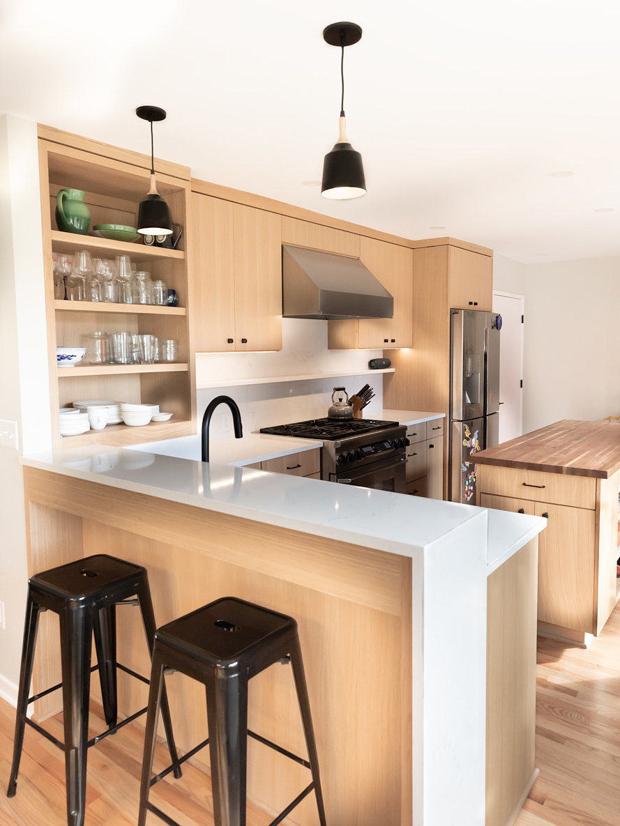 Peninsula with black metal stools looking toward range and full-height oak cabinets, Brooklyn Street kitchen remodel by Tweto Architecture