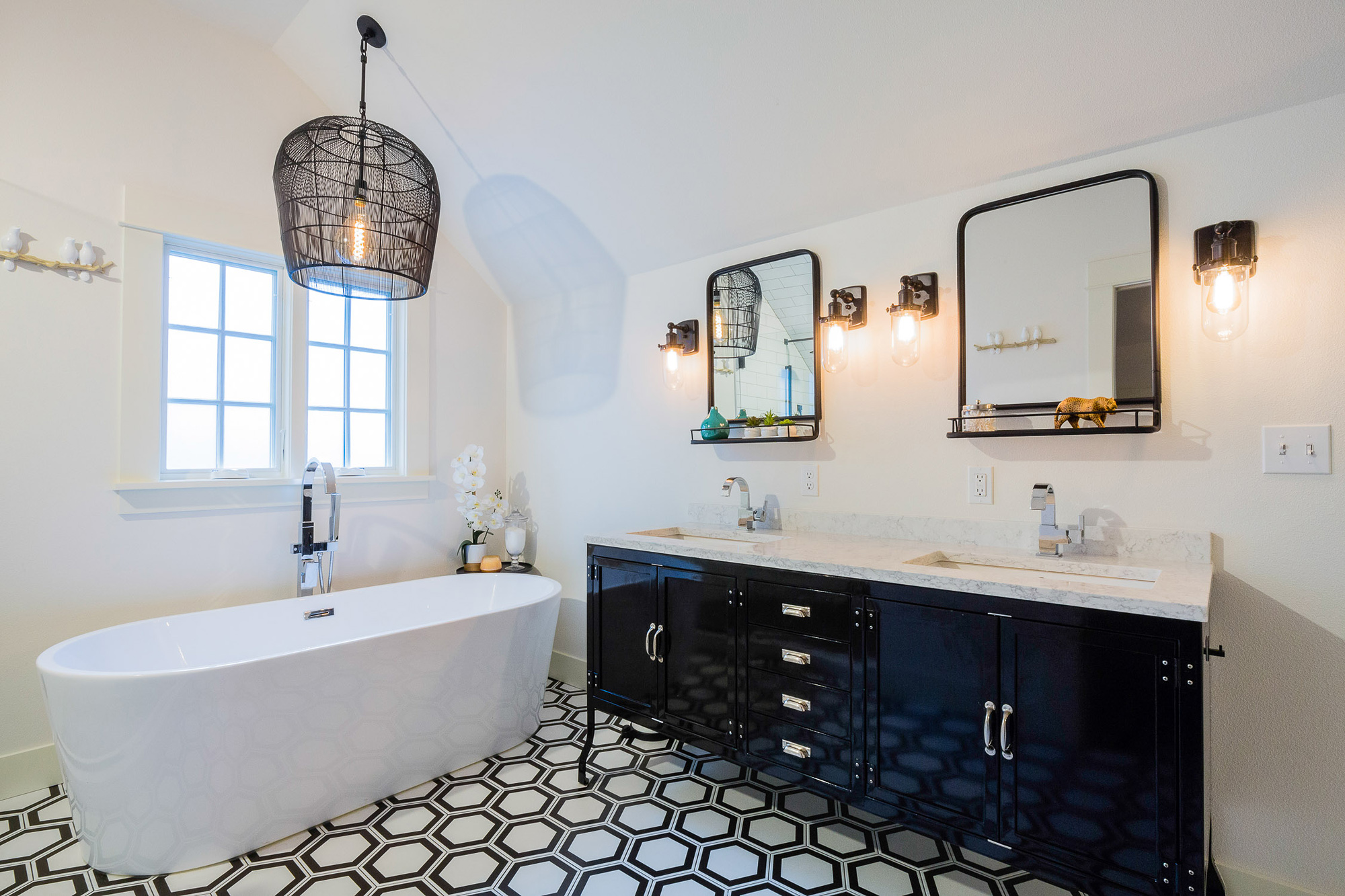 Double vanity with dark cabinet, two sinks, black-framed mirrors, and freestanding soaking tub in background, Carolina Primary Suite addition by Tweto Architecture