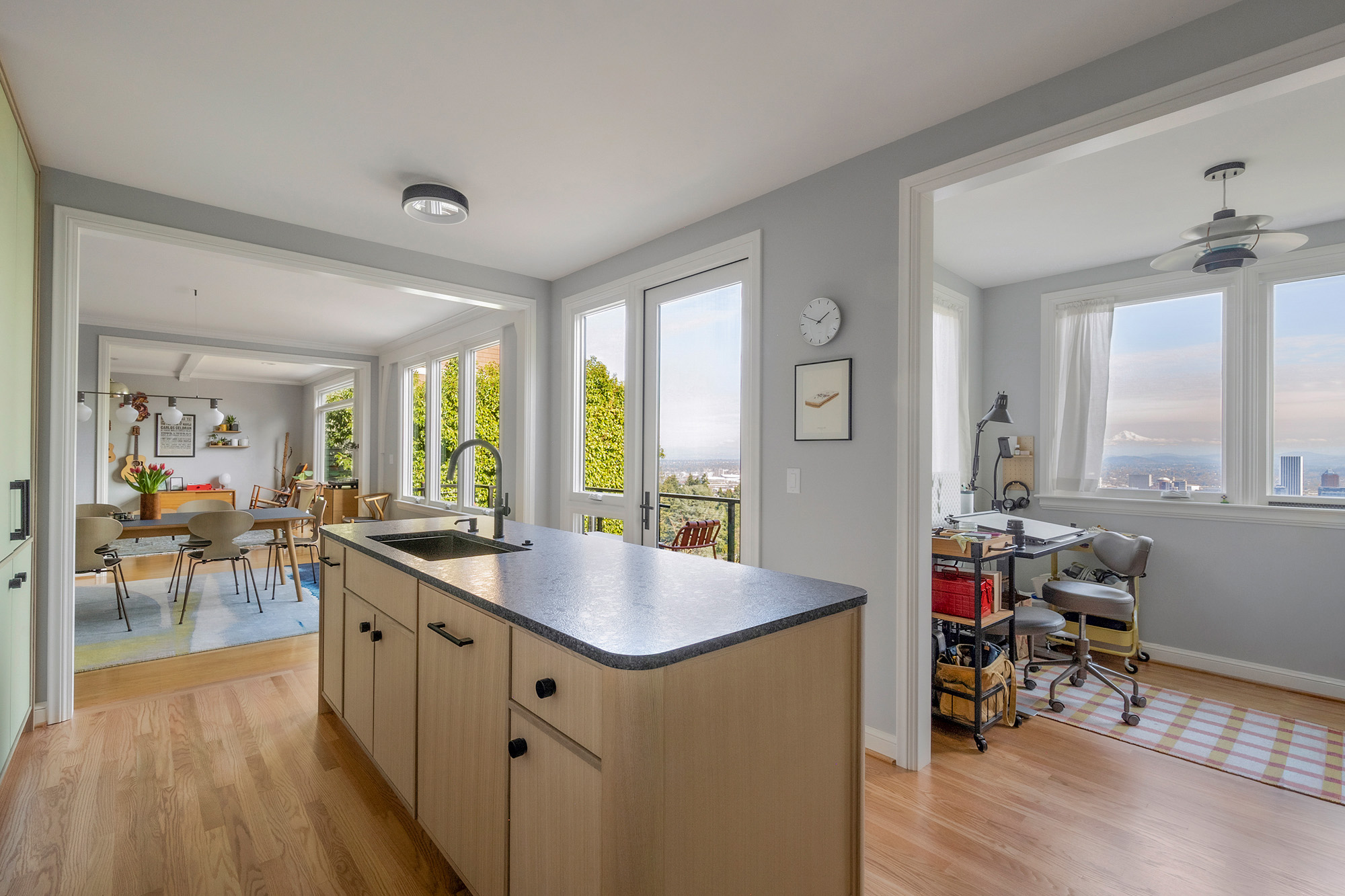 View from kitchen across island through terrace doors to Portland city views with Mount Hood in the distance, art studio nook to right, by Tweto Architecture