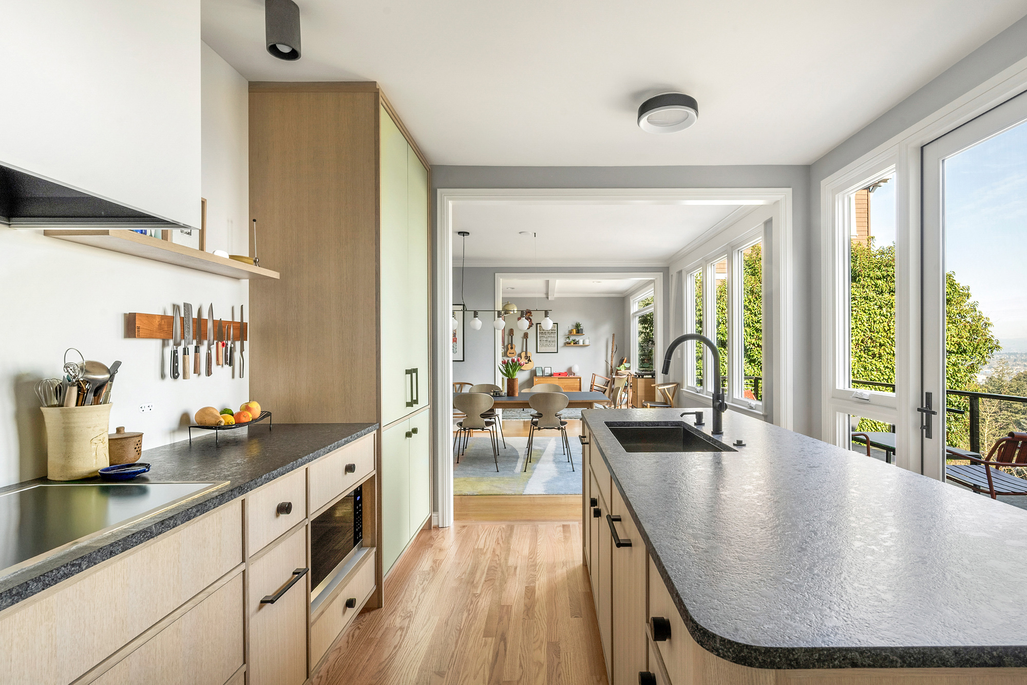 Kitchen looking toward dining room and terrace doors with Mount Hood view at right, island in foreground with new terrace door framing city view, by Tweto Architecture