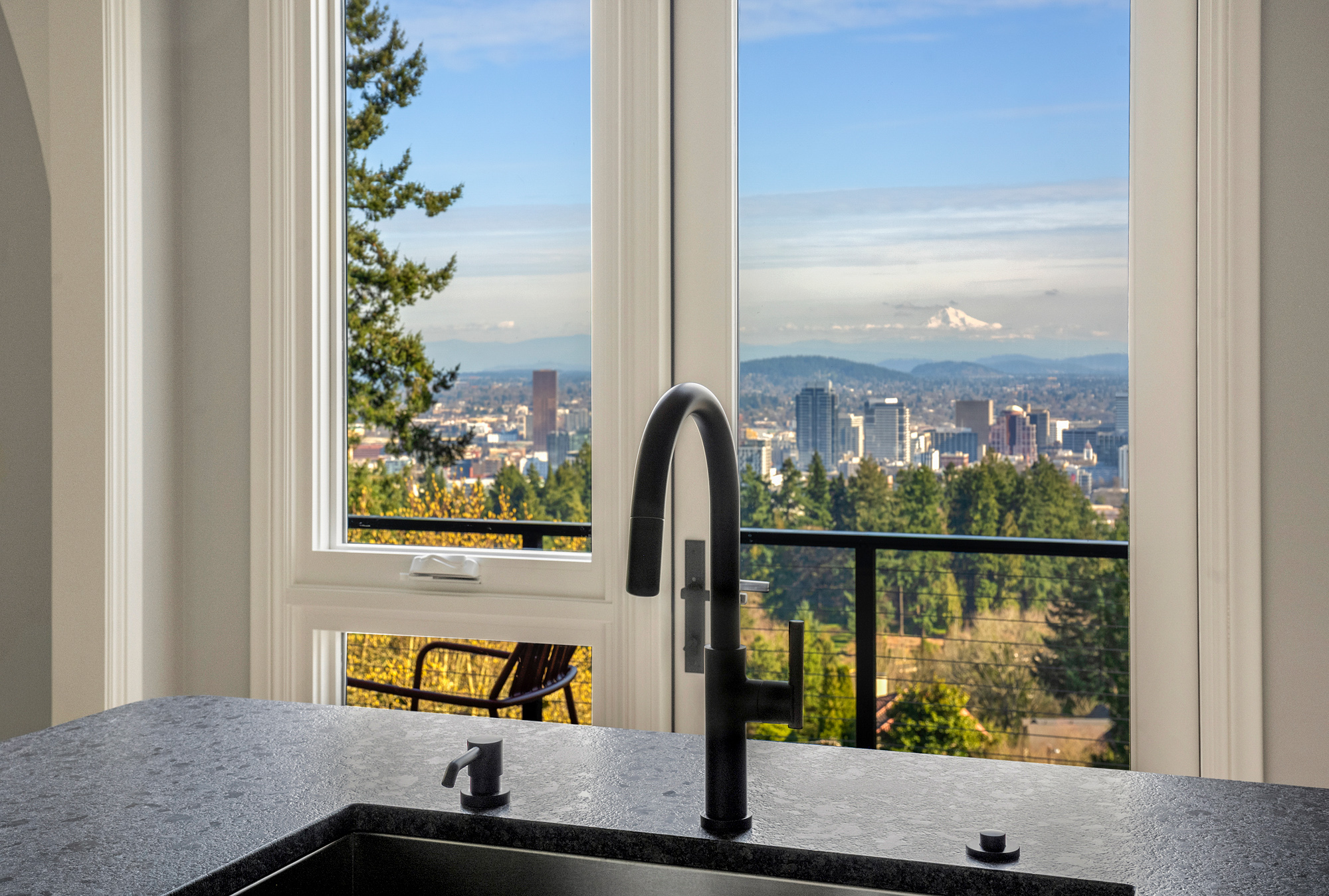 Island sink with black faucet looking through new full-height windows to Portland skyline and Mount Hood in the distance, by Tweto Architecture