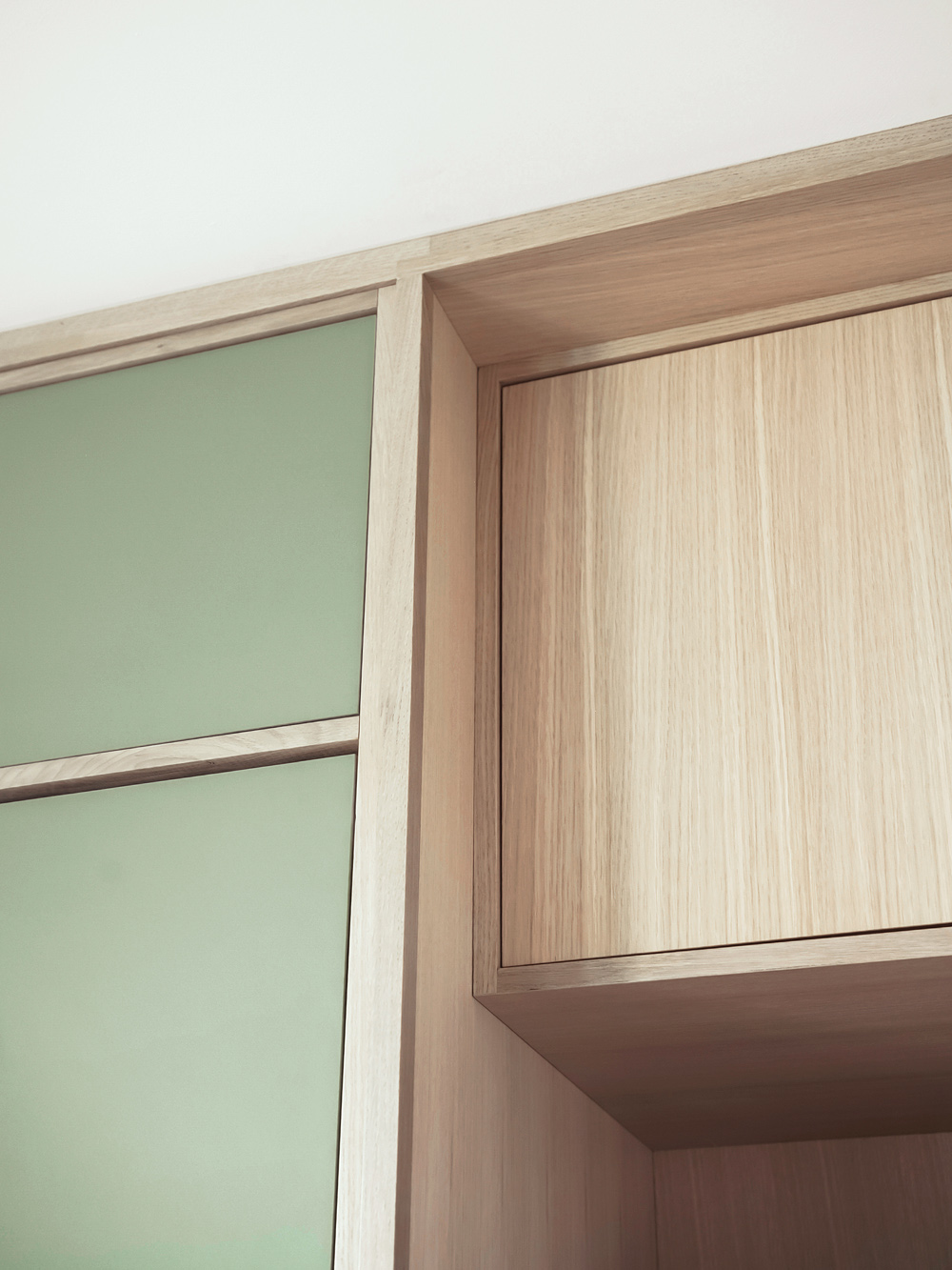 Cabinet corner detail showing sage linoleum panel meeting natural oak carcass at upper cabinet, by Tweto Architecture