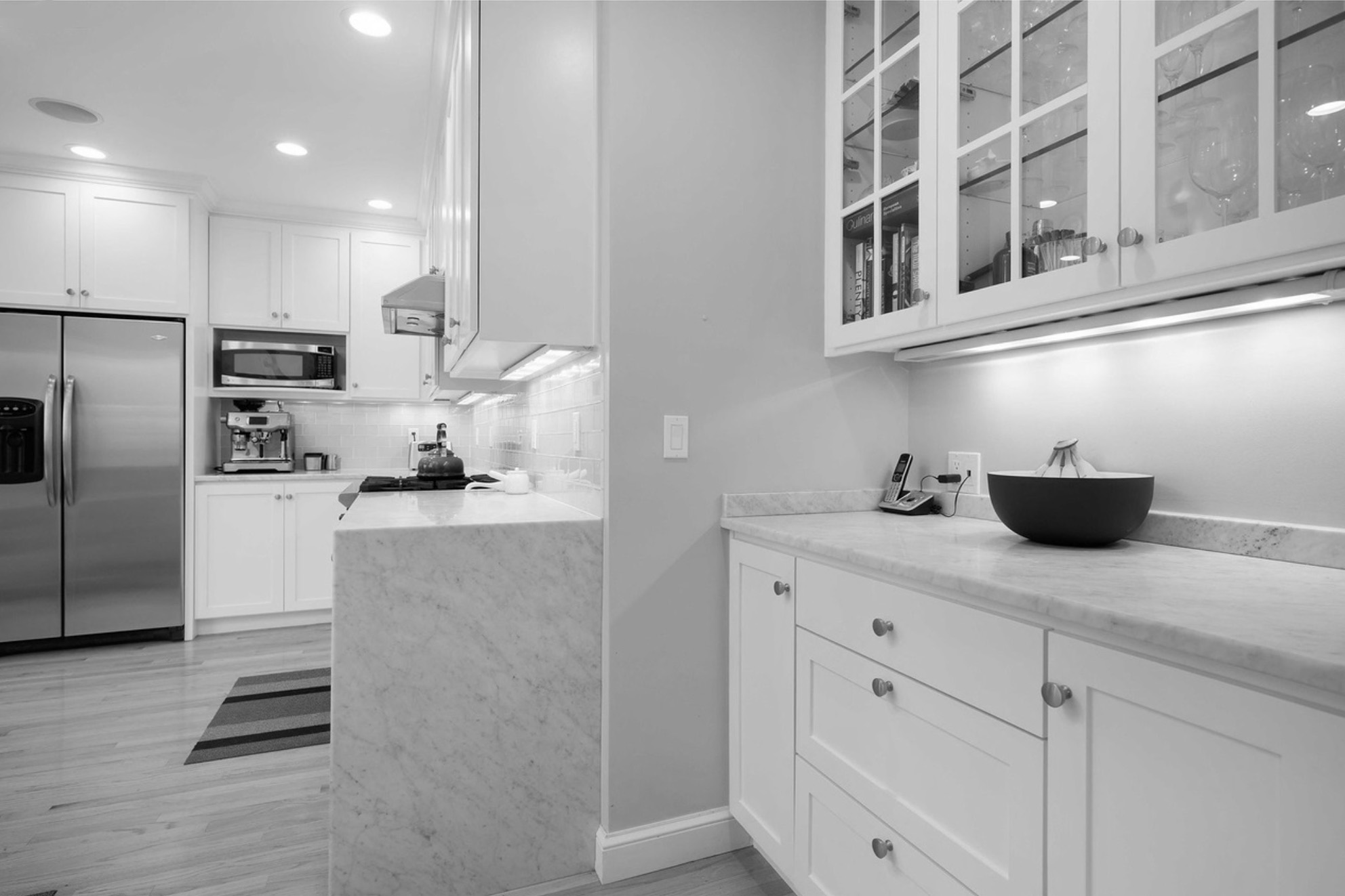 Existing kitchen before remodel with white shaker cabinets, marble peninsula with no views, and separate cramped layout, Champlain Drive Remodel