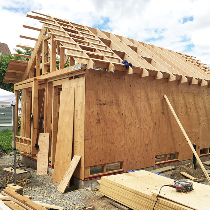 ADU framing under construction, showing wood structure and gable roof taking shape, by Tweto Architecture