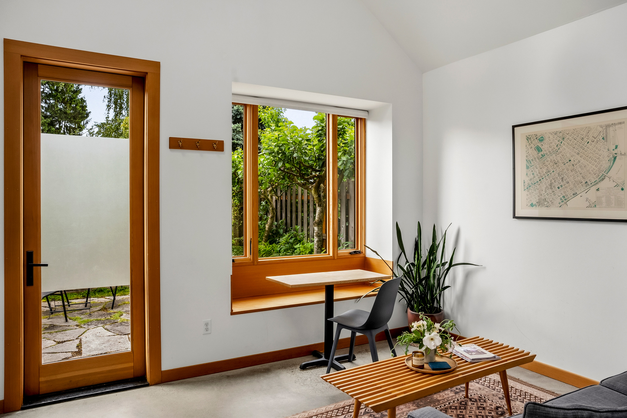 Glazed door to the patio beside a built-in bay window desk overlooking the garden, Irving Park ADU by Tweto Architecture