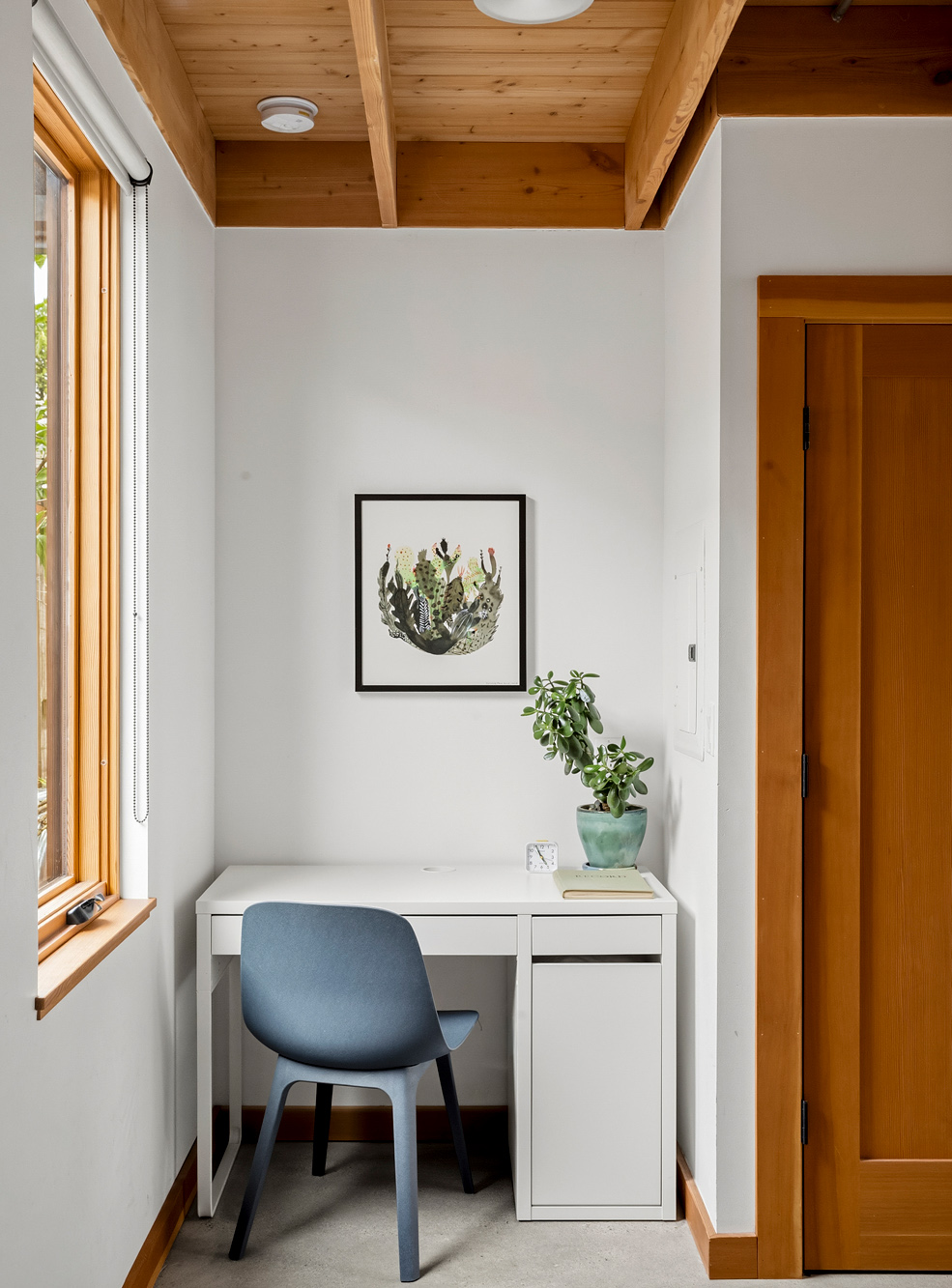Desk nook with exposed wood ceiling, white desk, blue chair, and a window looking into the garden, Irving Park ADU by Tweto Architecture