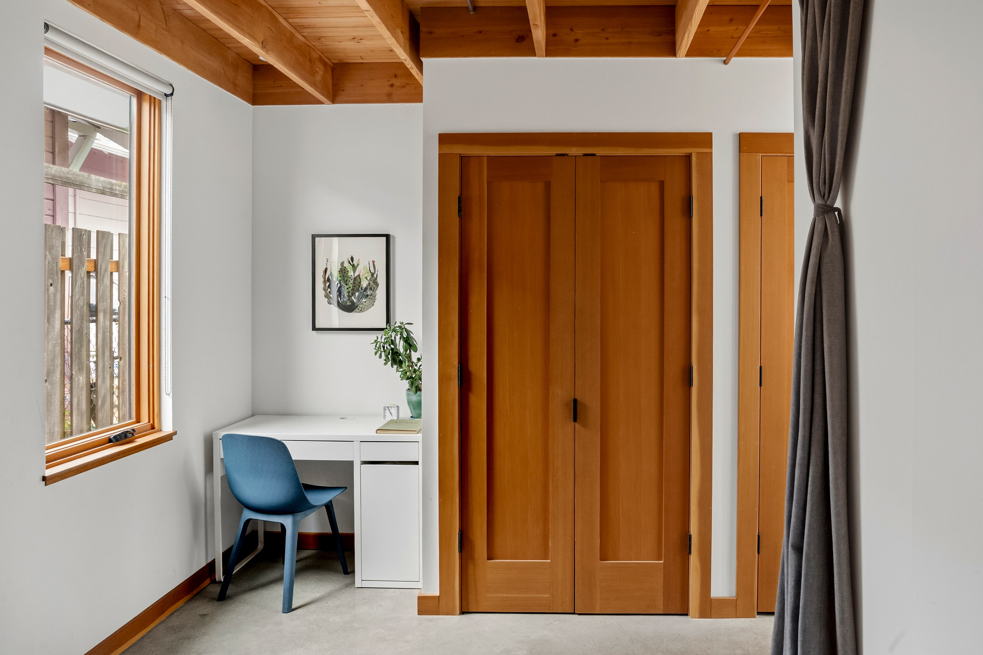 Bedroom corner with built-in Douglas Fir closet doors, exposed wood ceiling, and a desk nook beside the window, Irving Park ADU by Tweto Architecture