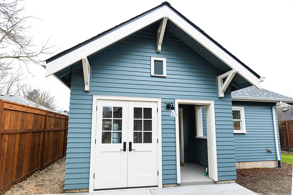Irvington ADU exterior with blue-grey lap siding, white craftsman trim, gable roof, and French doors, NE Portland by Tweto Architecture