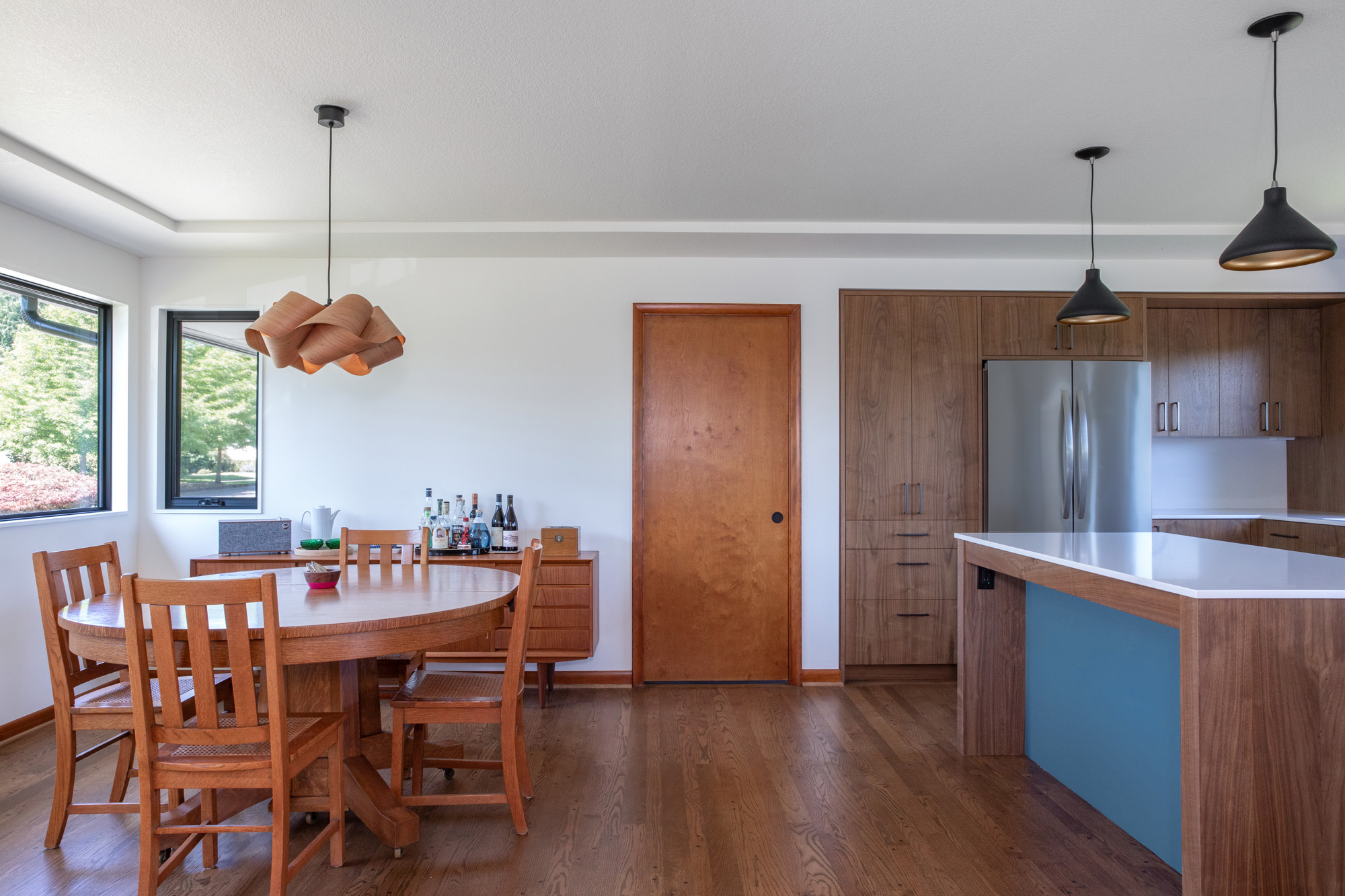 Dining room looking toward the kitchen island with walnut cabinetry and stainless refrigerator beyond, Kelly Street remodel by Tweto Architecture