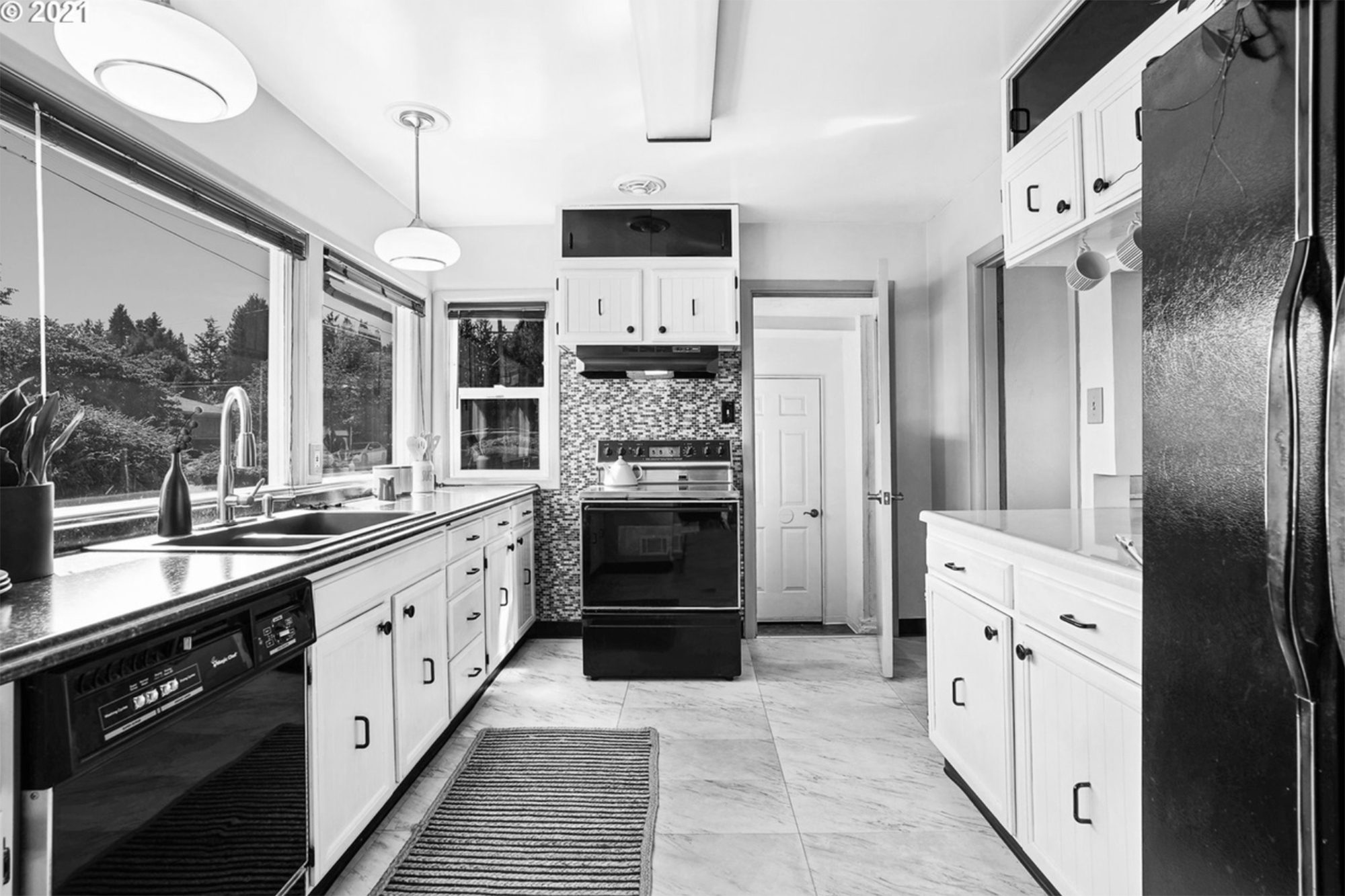 Original galley kitchen with white cabinets, tile floor, and small windows, before the Kelly Street remodel