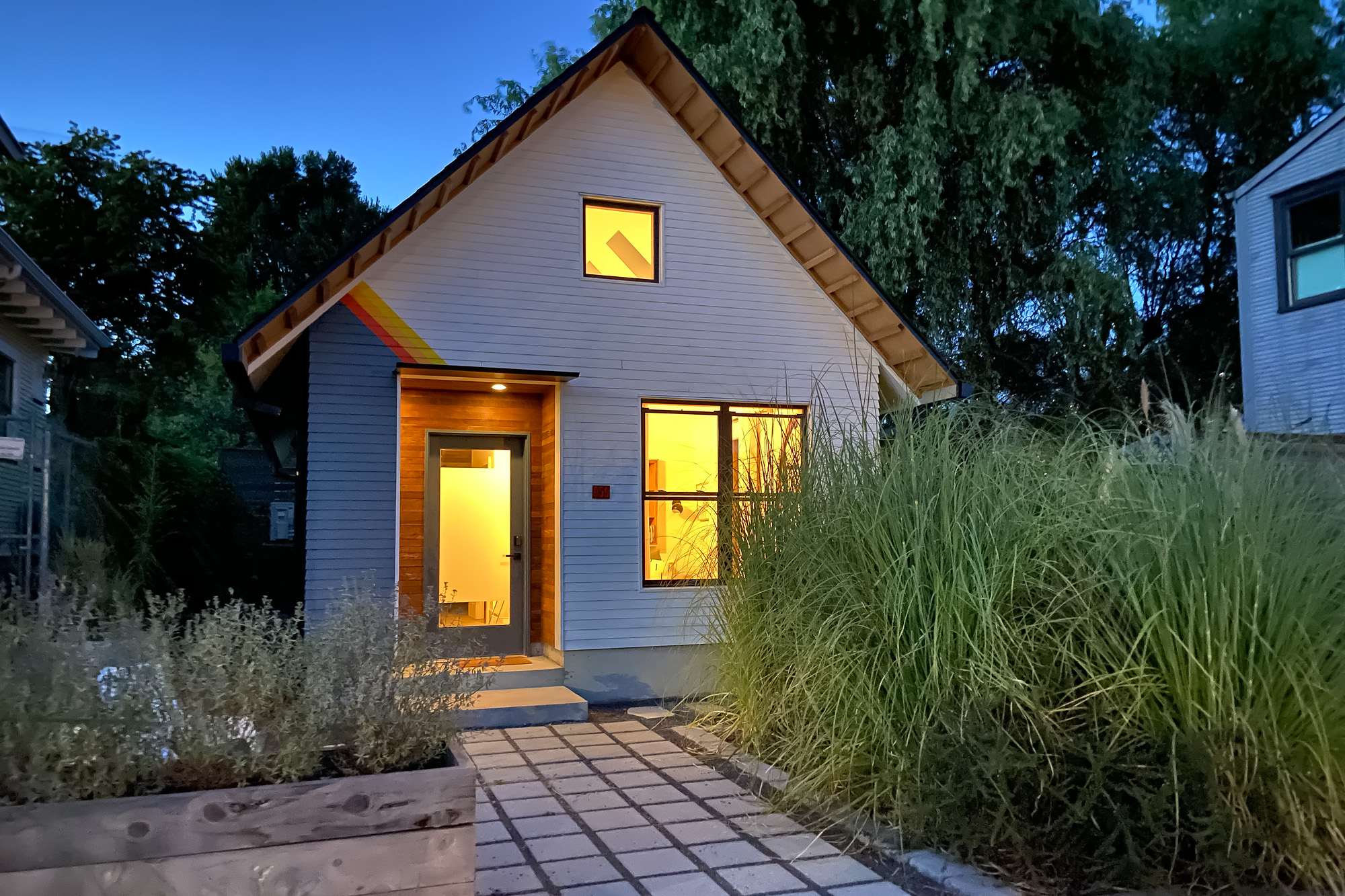 Mason Street ADU at dusk with interior lights on and stepping stone path leading to the lit entry, NE Portland, by Tweto Architecture