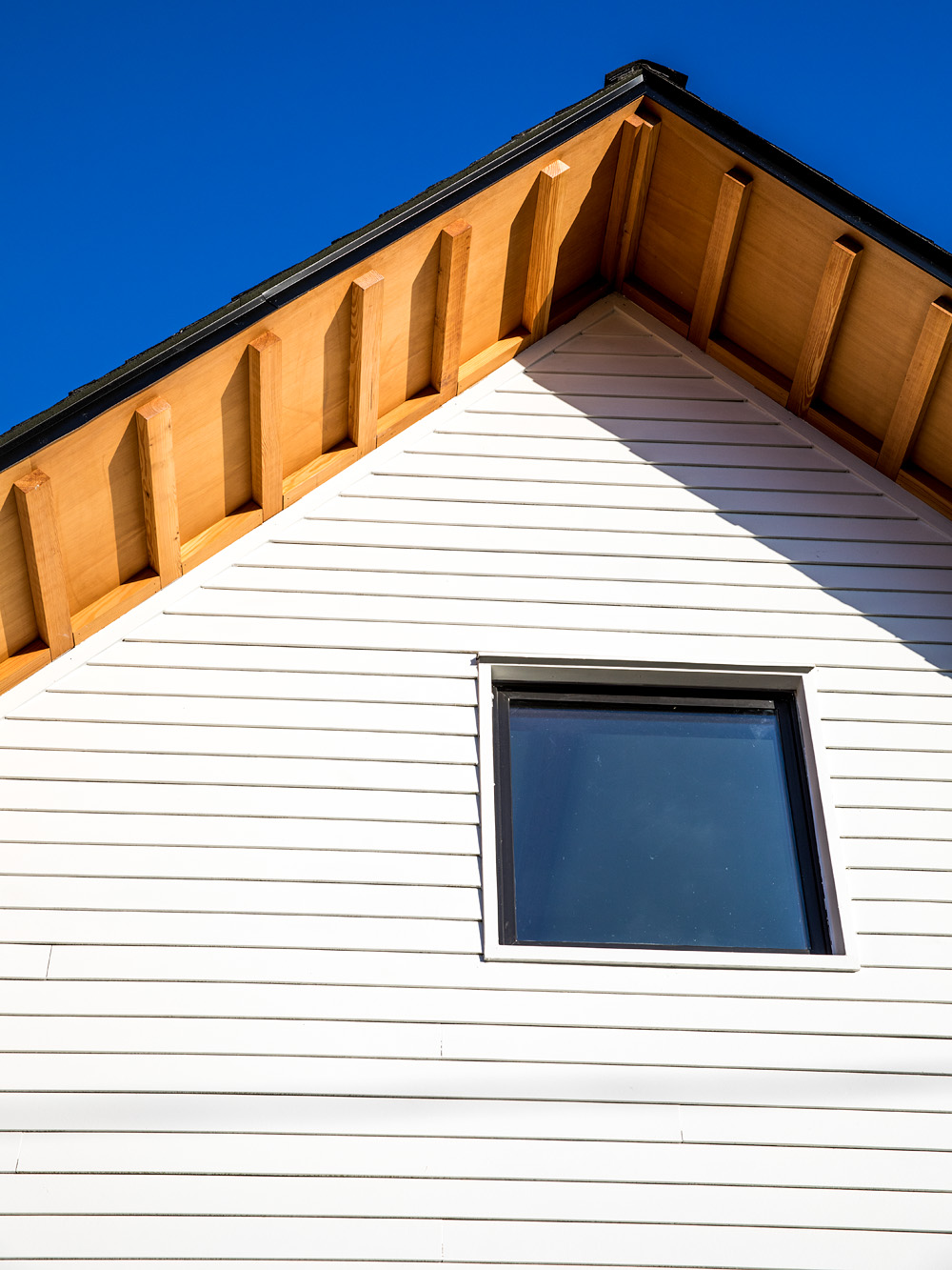 Gable peak close-up showing exposed fir rafter tails under the deep eave, Mason Street ADU by Tweto Architecture
