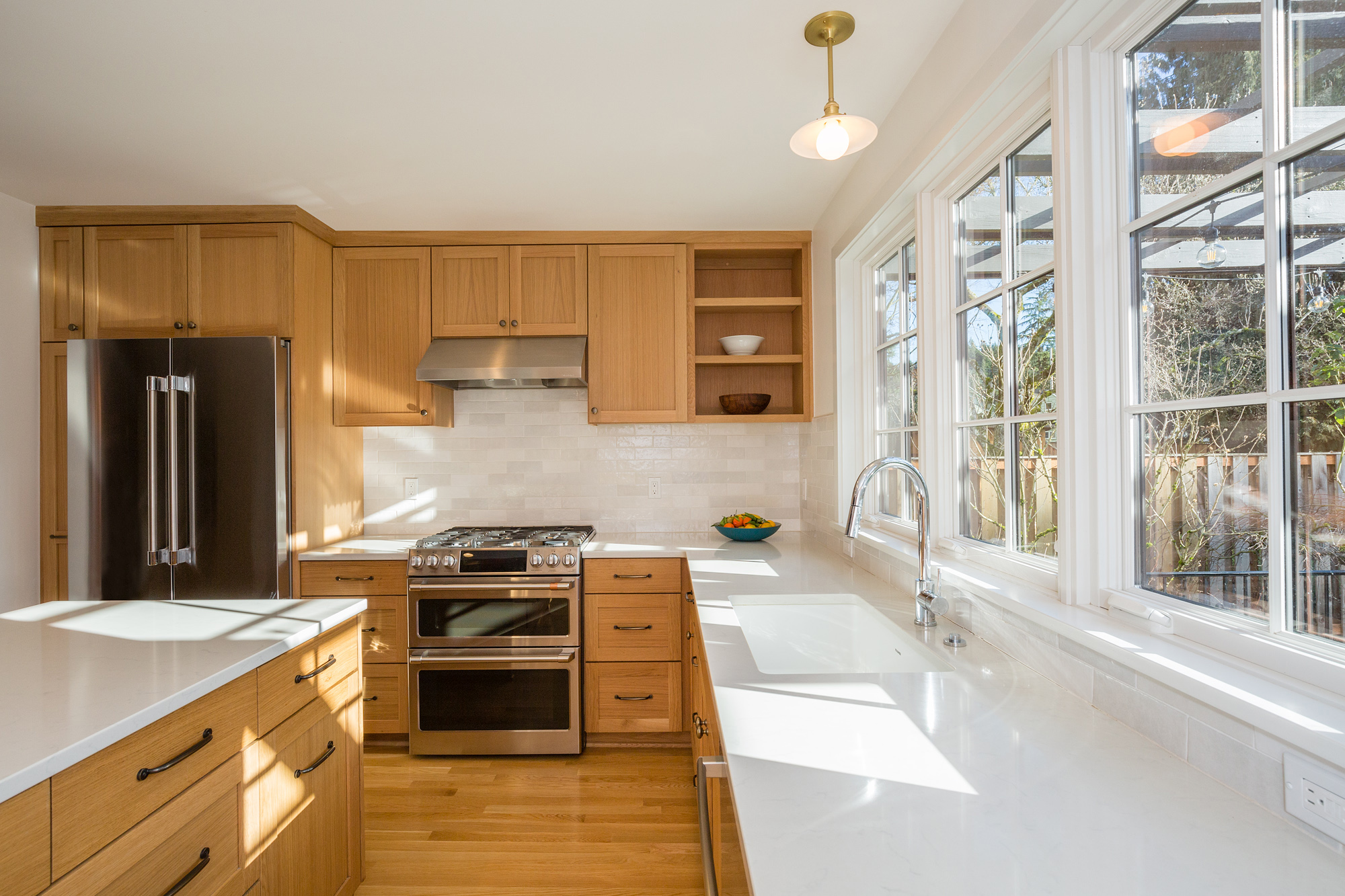 Kitchen from dining room side showing range, double oven, integrated fridge, and casement windows at right, Mt. Tabor Tudor remodel by Tweto Architecture
