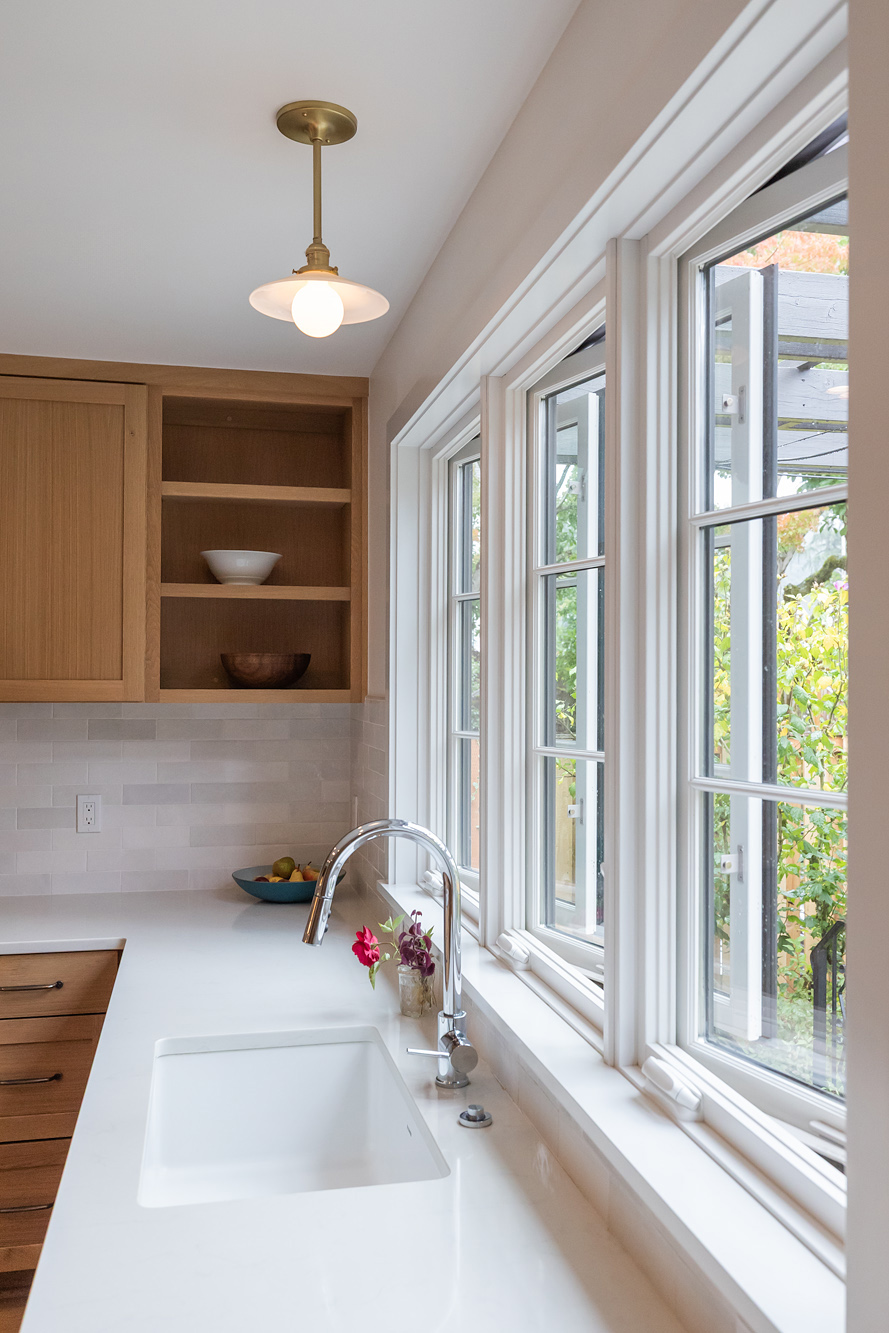 Kitchen sink wall with three casement windows looking out to backyard plantings, Mt. Tabor Tudor remodel by Tweto Architecture