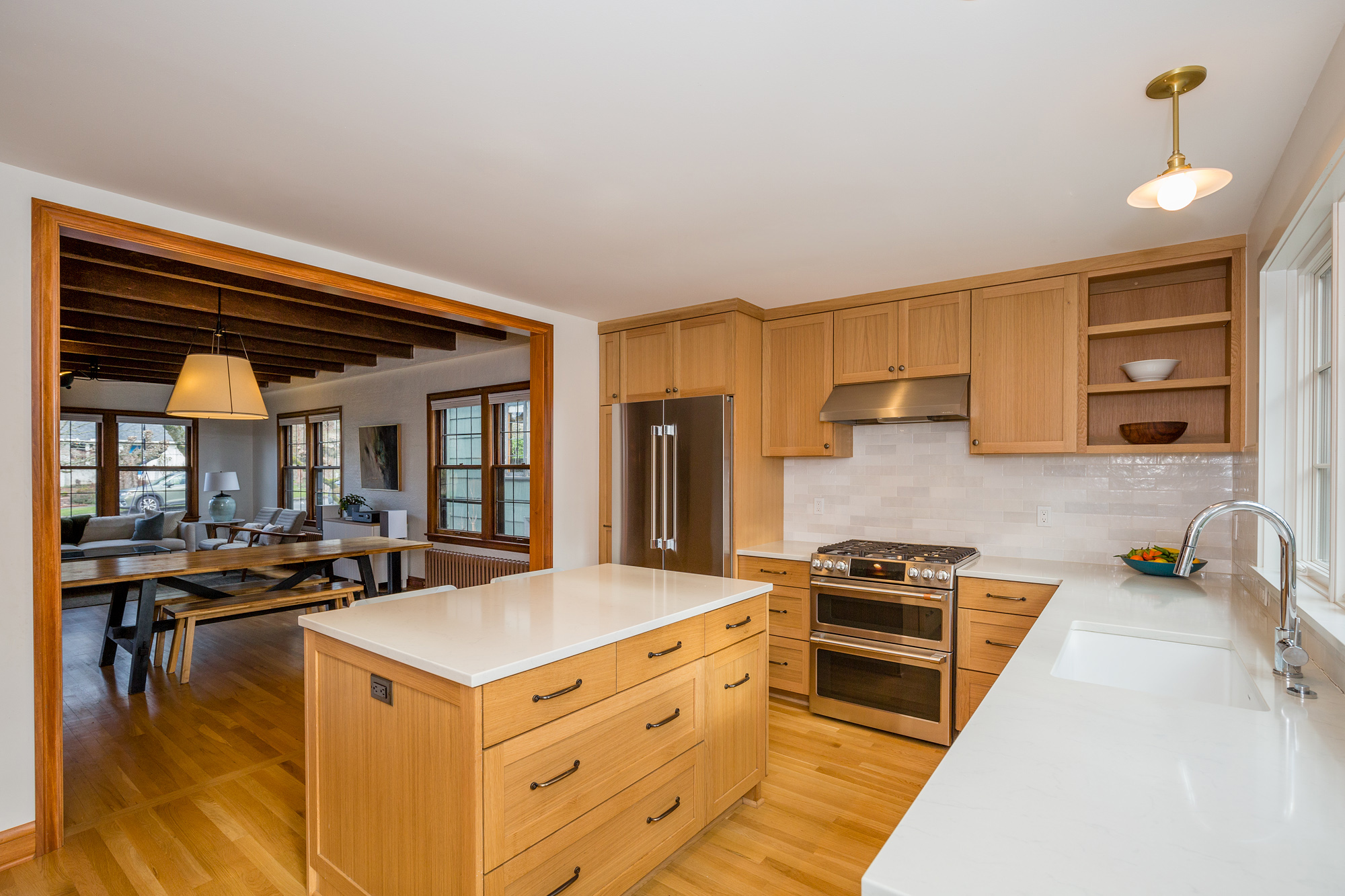 Kitchen opening to dining room with island and storage wall visible, original Tudor beamed ceiling beyond, Mt. Tabor Tudor remodel by Tweto Architecture