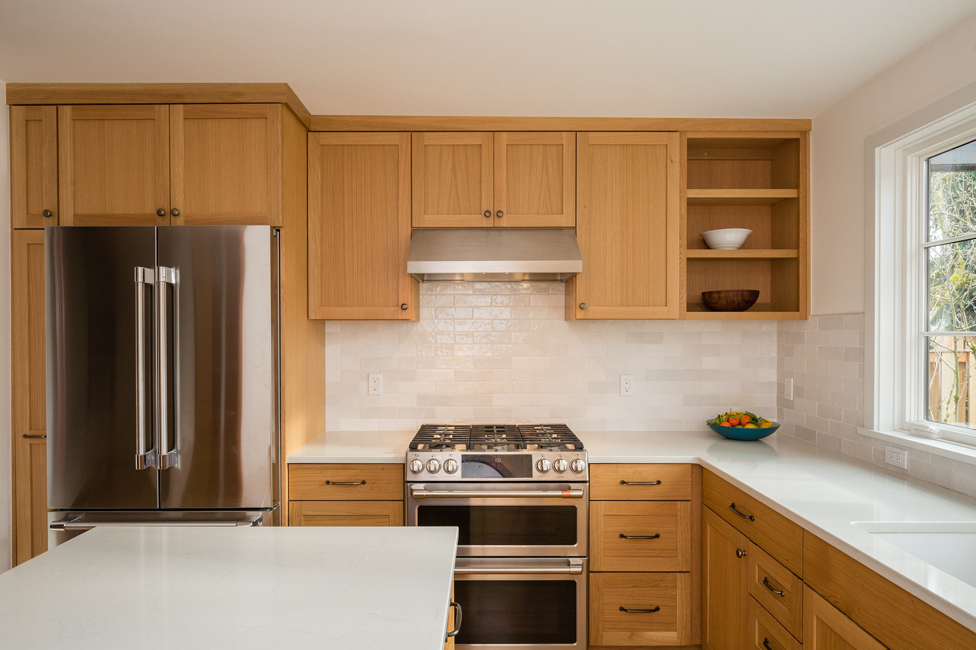 Range wall with double oven and integrated refrigerator, oak cabinetry and subway tile backsplash, Mt. Tabor Tudor remodel by Tweto Architecture