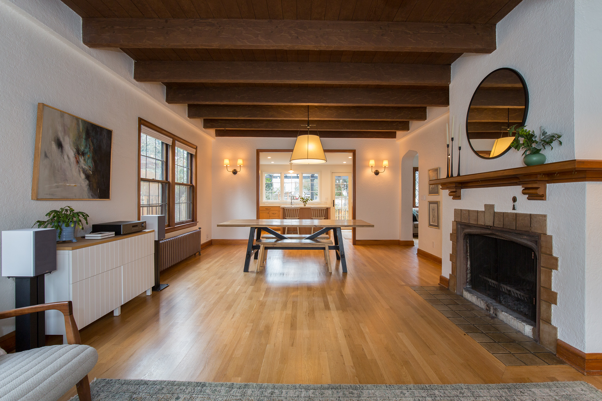 Living room with original fireplace and beamed ceiling looking through to the kitchen at the rear of the house, restored main floor circulation, Mt. Tabor Tudor remodel by Tweto Architecture