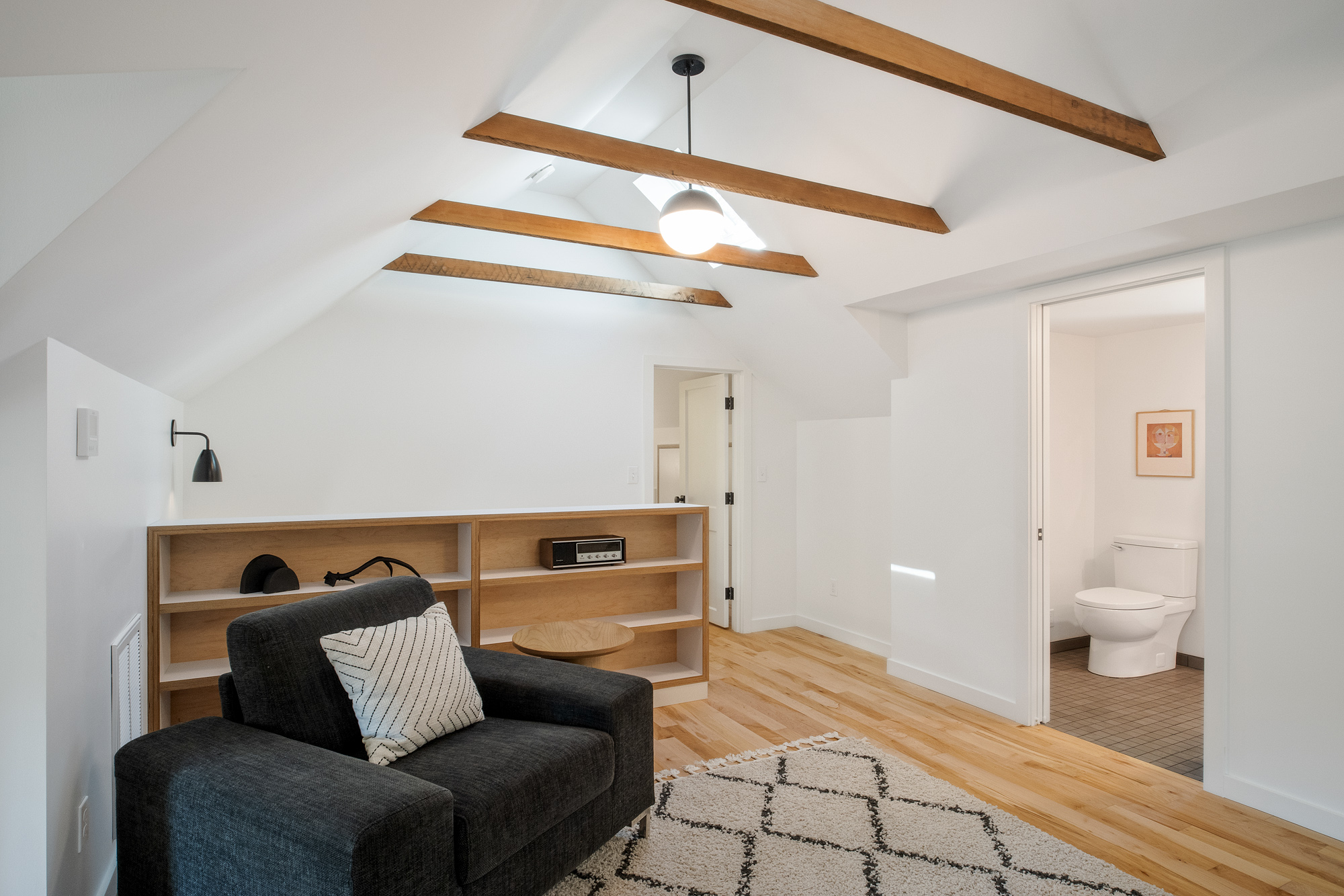 Vaulted attic family room looking toward the remodeled bathroom, exposed fir collar ties above, NE 9th Remodel by Tweto Architecture