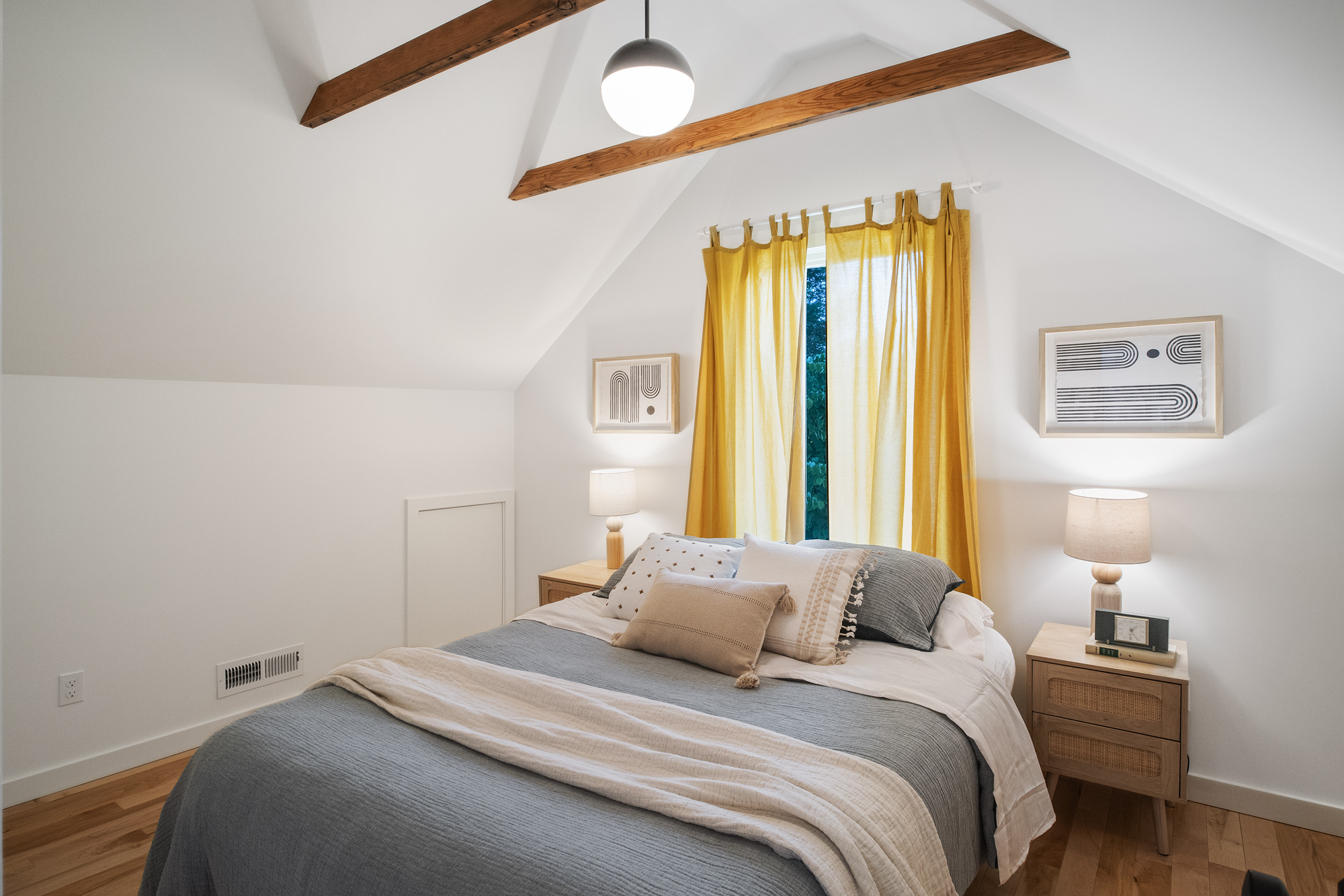 Attic bedroom with vaulted ceiling, exposed fir collar tie, and yellow-curtained window, NE 9th Remodel by Tweto Architecture