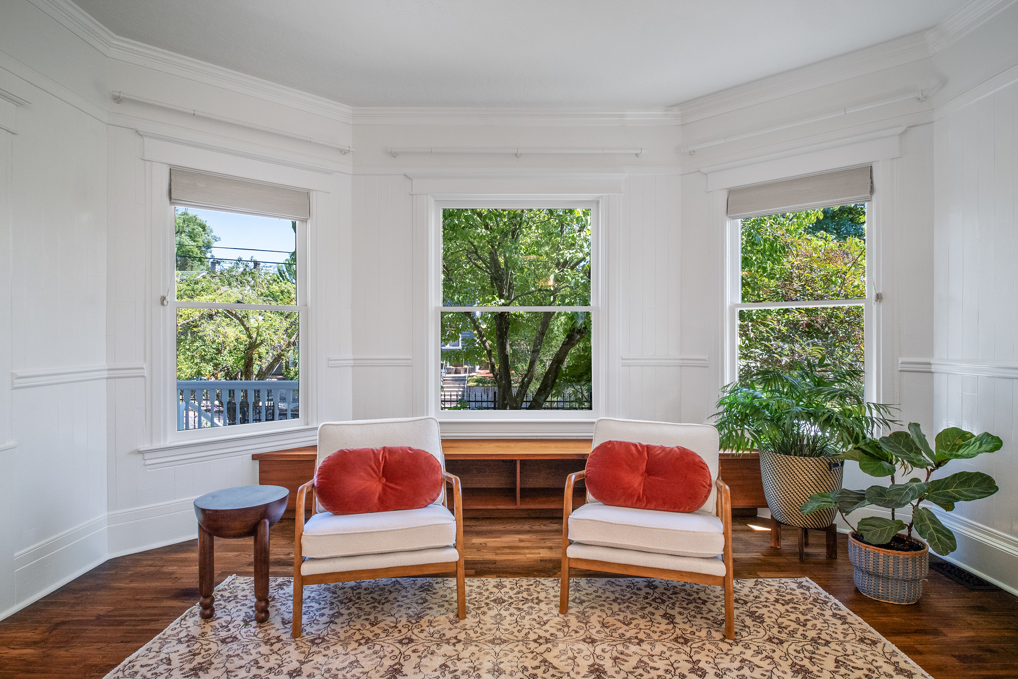 Restored curved bay window with three sash windows and wood window seat in the main floor living room, NE 9th Remodel by Tweto Architecture, NE Portland