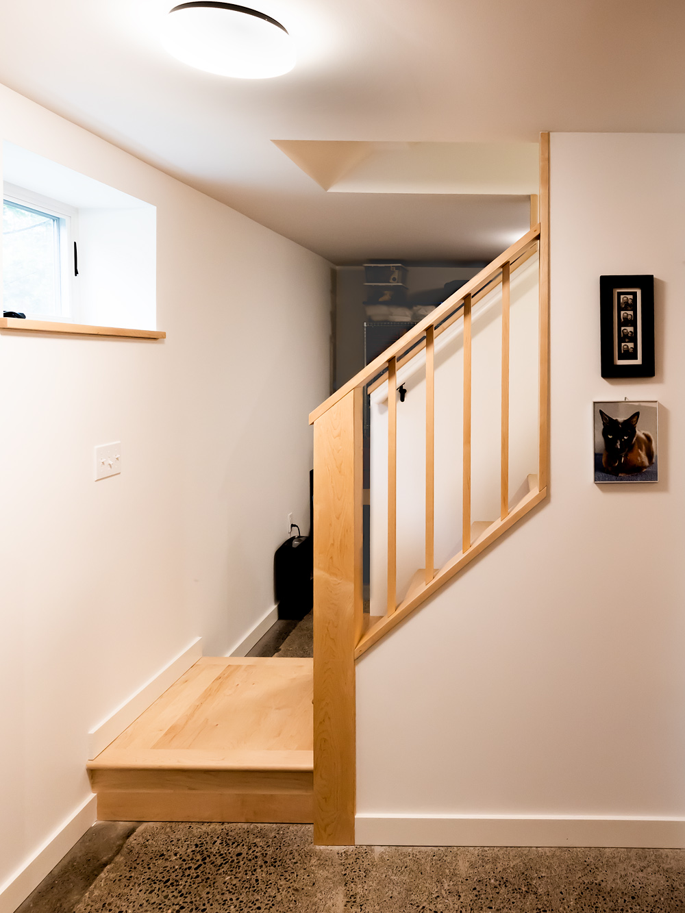 Maple stair with open railing leading from the polished concrete basement floor up toward the main level, NE 9th Remodel by Tweto Architecture