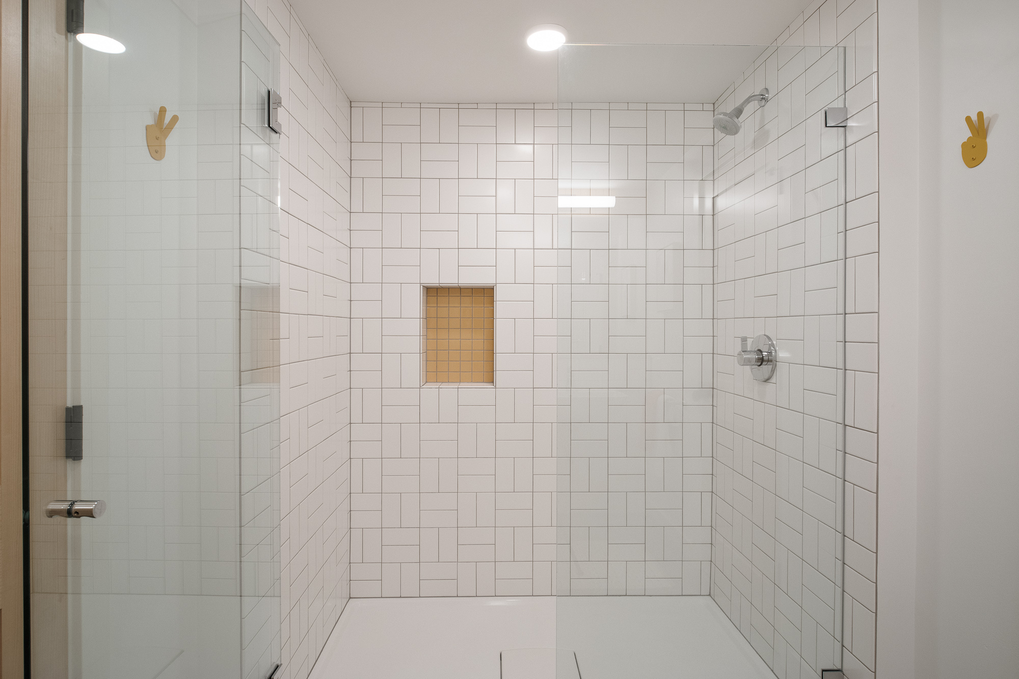 Full-height white subway tile walk-in shower with glass door and amber tile accent niche, NE 9th Remodel by Tweto Architecture