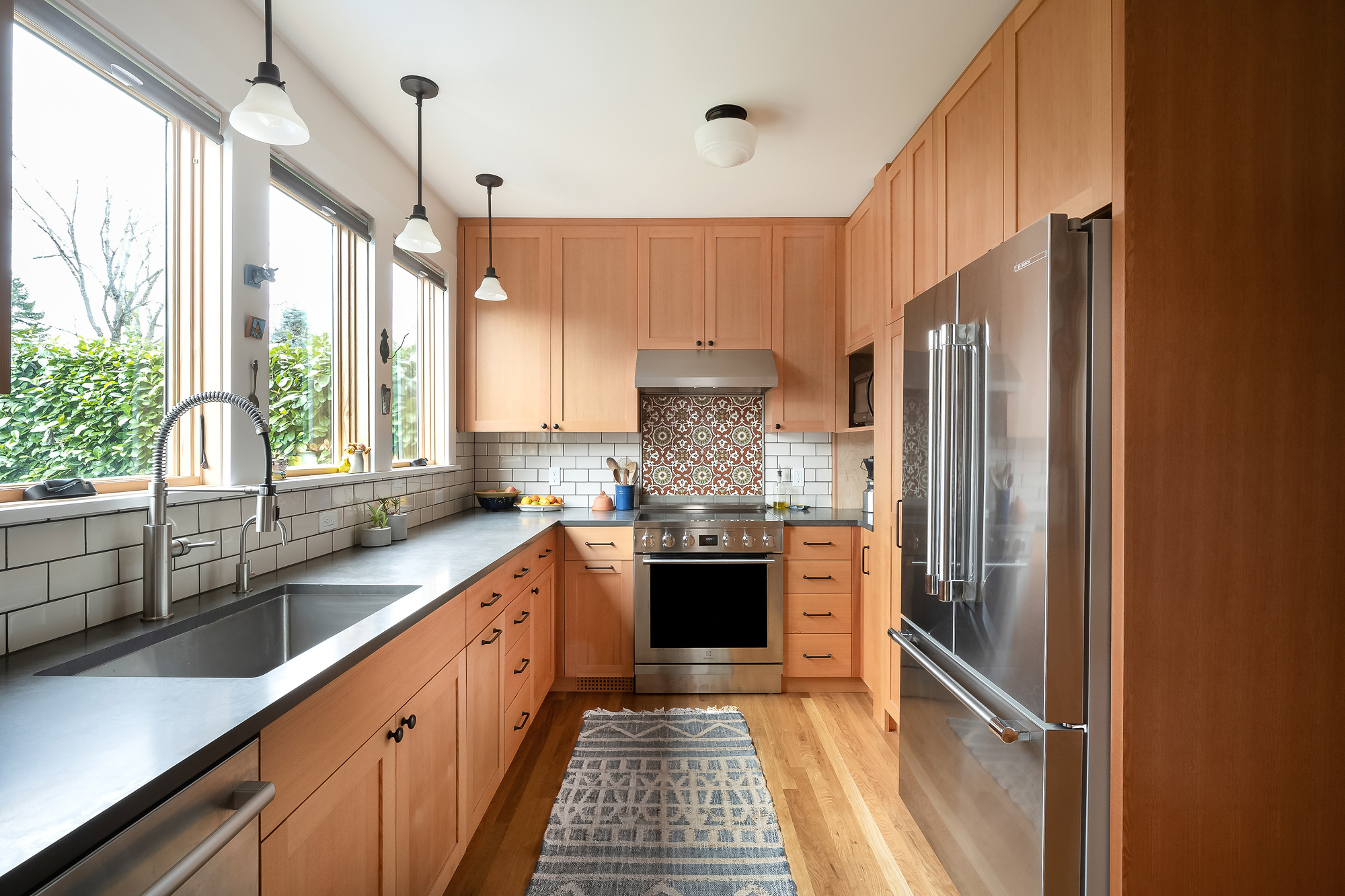 Wide view of remodeled kitchen showing sink wall, range with decorative tile accent, and vertical grain Douglas Fir cabinets, Sabin Kitchen by Tweto Architecture, NE Portland