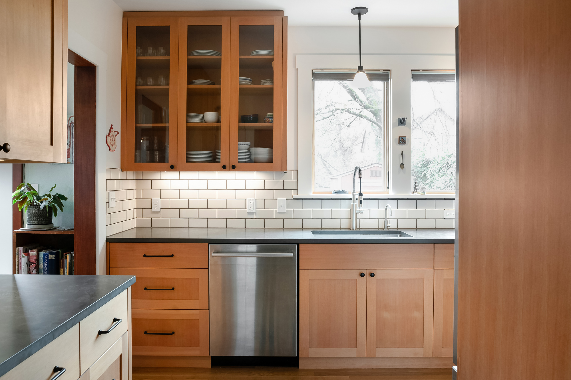 Glass-front upper cabinets near the sink showing dishes, Sabin Kitchen kitchen remodel by Tweto Architecture, NE Portland