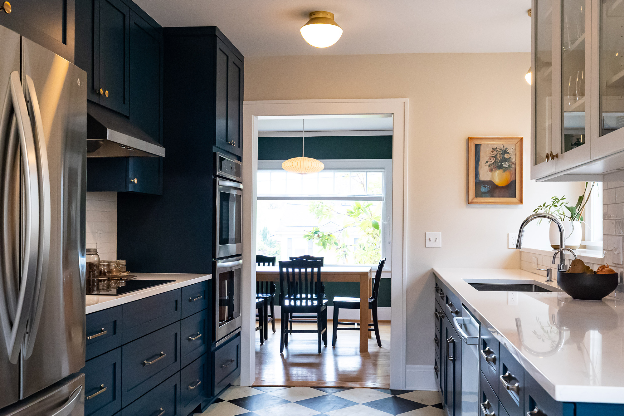 Galley kitchen looking toward dining room opening, interior wall with refrigerator and double wall ovens, exterior wall with sink and deep window sill beyond, Stanton Street Kitchen by Tweto Architecture