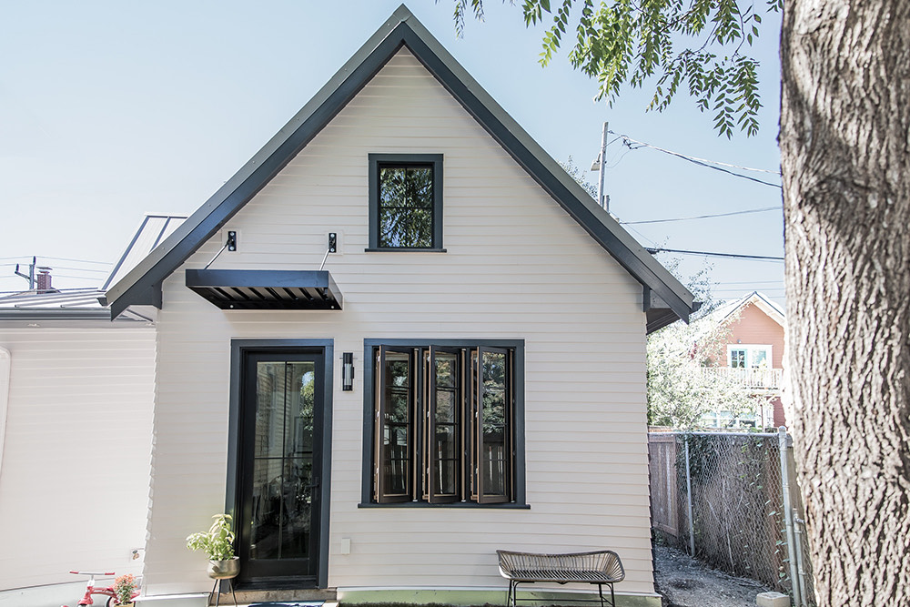 Vancouver Avenue ADU rear exterior with white siding, dark trim, and large folding wood-framed windows opening to a private yard, North Portland by Tweto Architecture